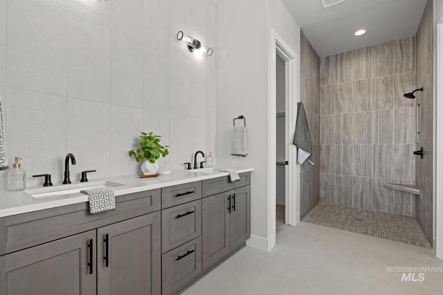 Full bath featuring walk in shower, double vanity, tile walls, light tile patterned floors, and recessed lighting