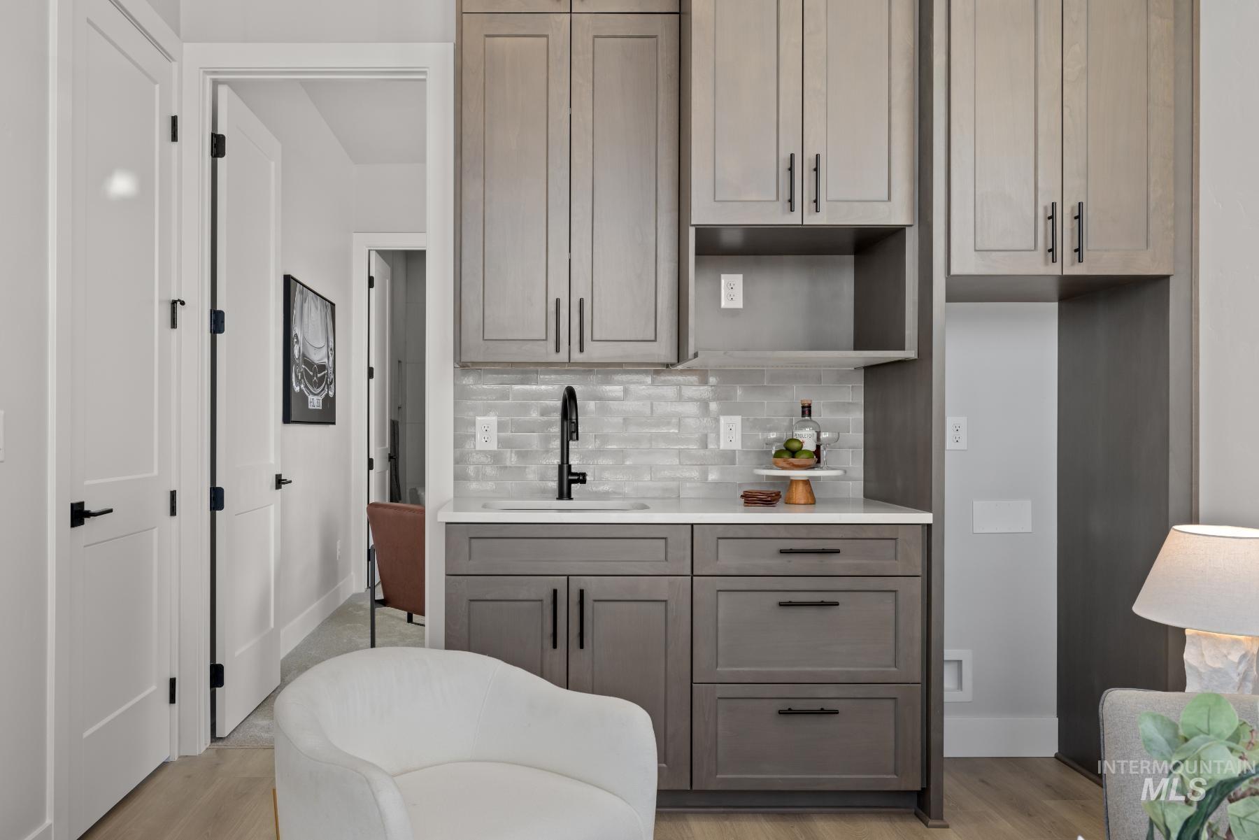 Kitchen featuring light stone counters, decorative backsplash, light wood-type flooring, and open shelves