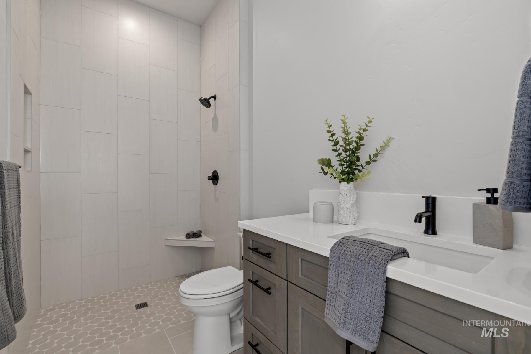 Full bath featuring vanity, a tile shower, and tile patterned floors