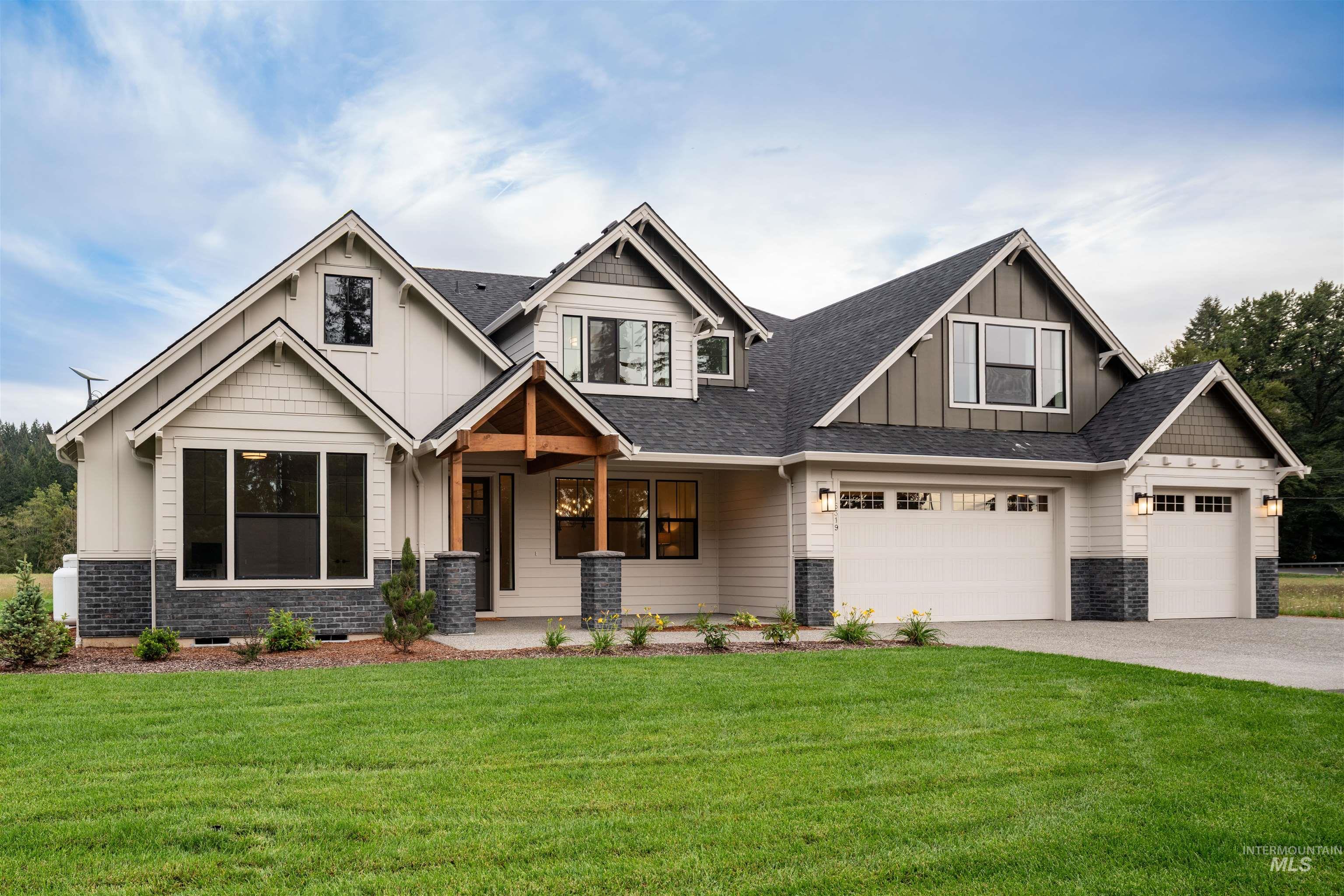 Craftsman house featuring board and batten siding, a front lawn, driveway, and a shingled roof