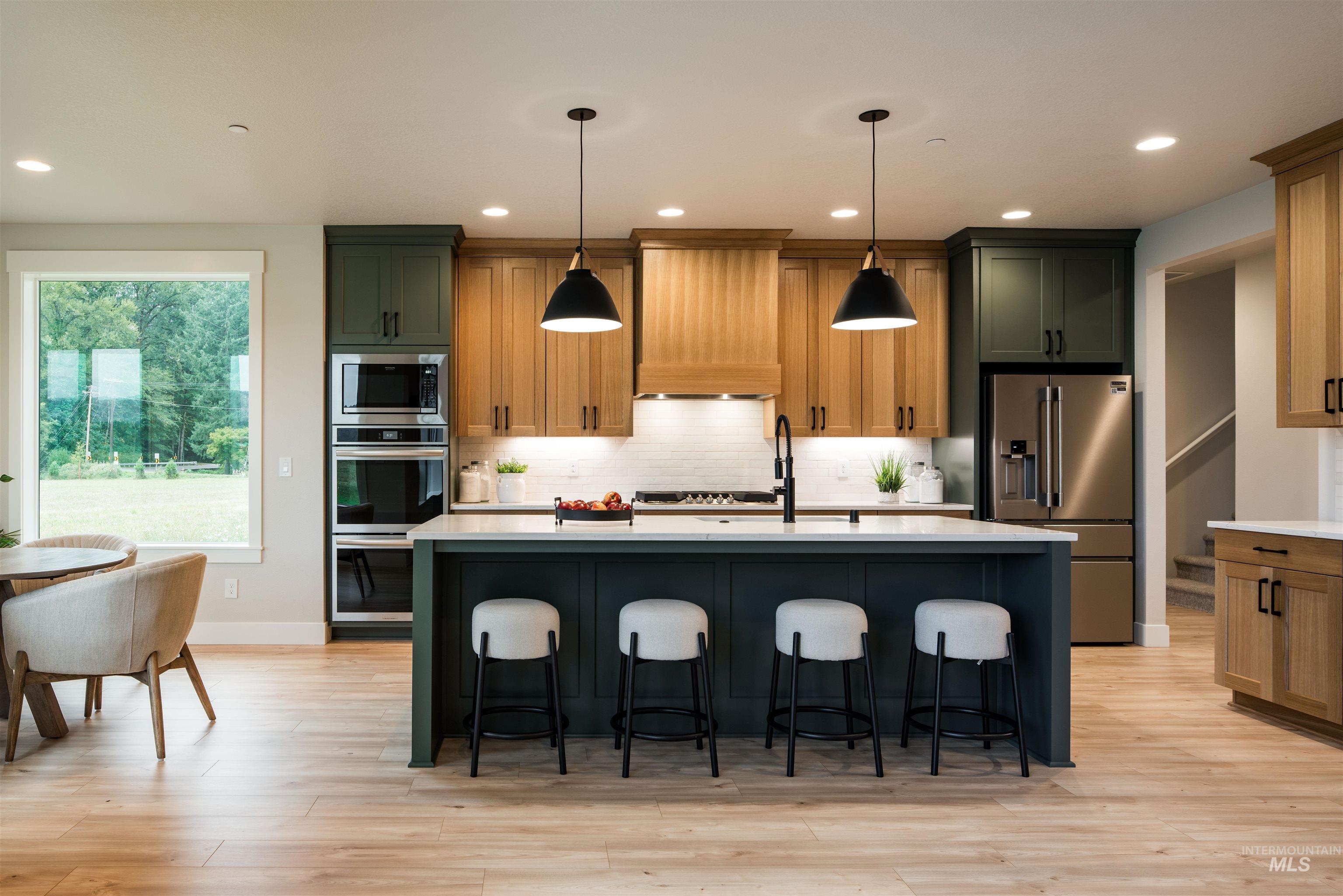 Kitchen featuring tasteful backsplash, stainless steel appliances, recessed lighting, a kitchen breakfast bar, and hanging light fixtures