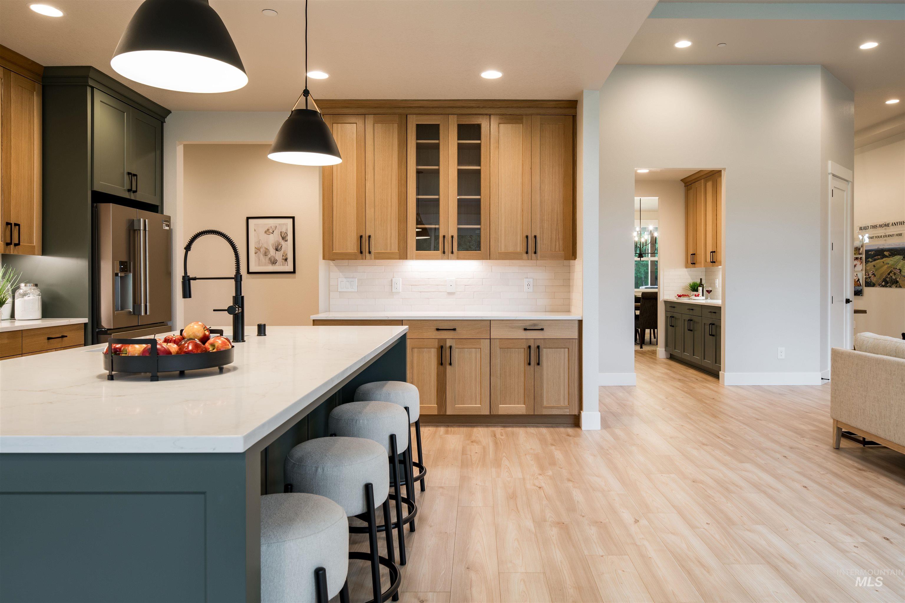 Kitchen featuring tasteful backsplash, recessed lighting, pendant lighting, high quality fridge, and light stone countertops