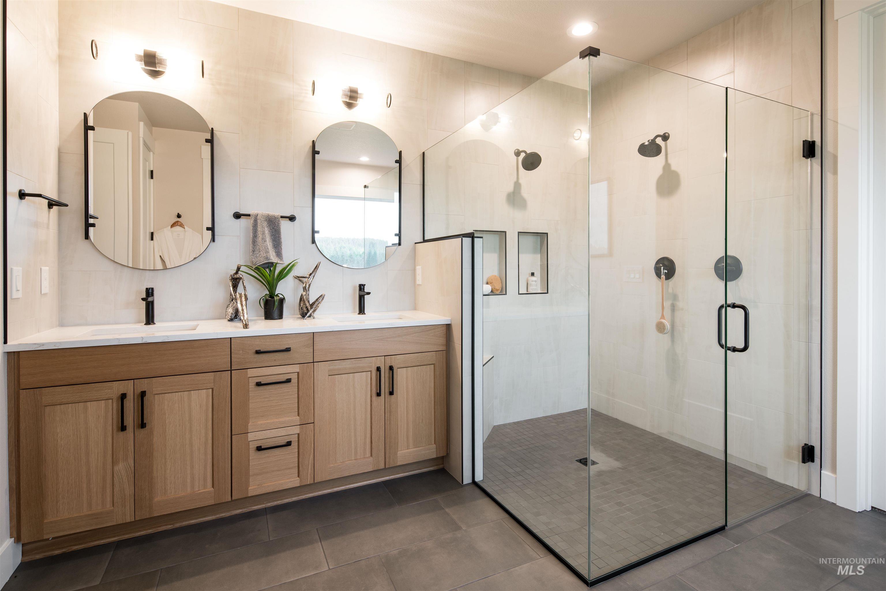 Bathroom with a stall shower, double vanity, and tile walls