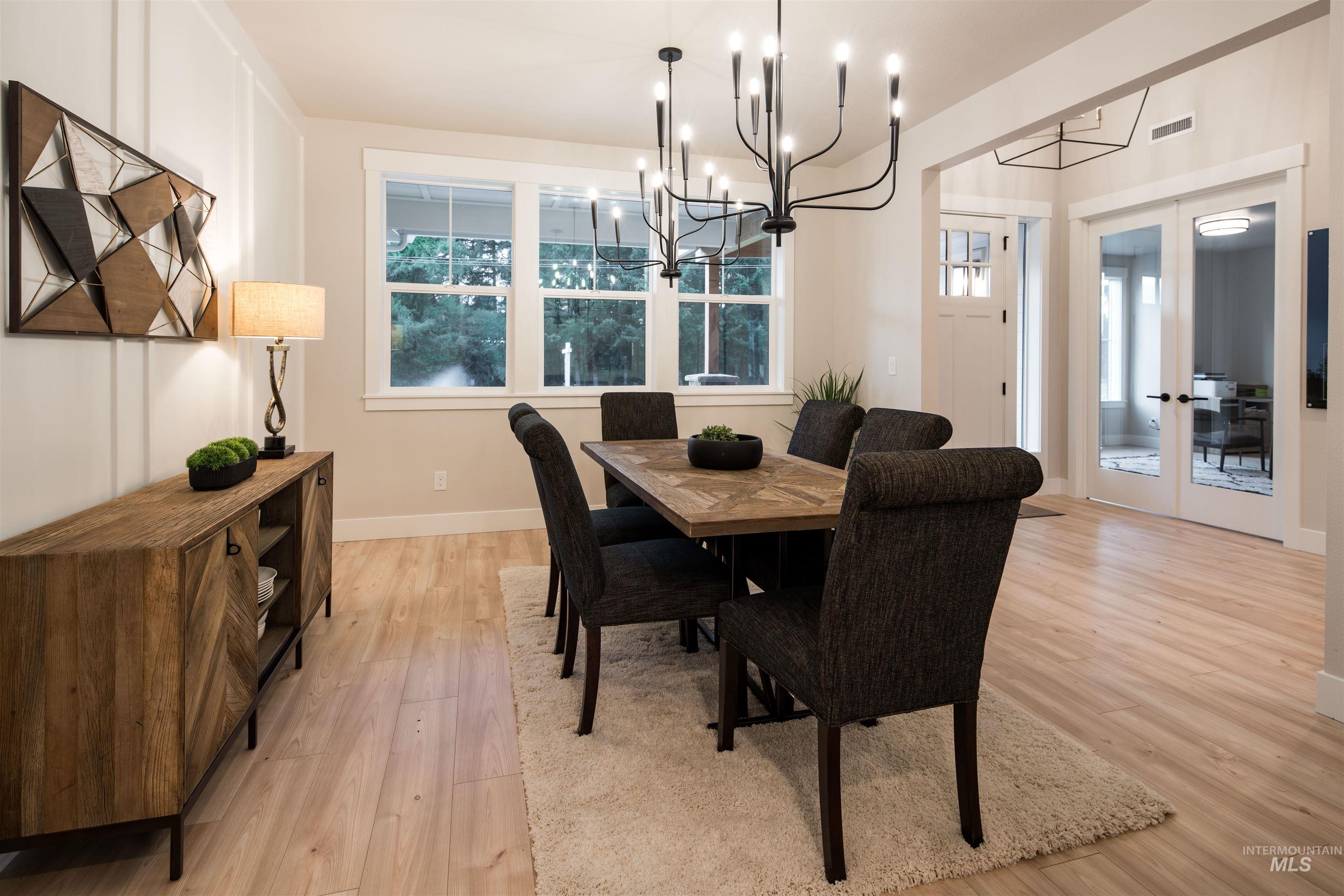 Dining area with light wood-type flooring, plenty of natural light, french doors, and a chandelier