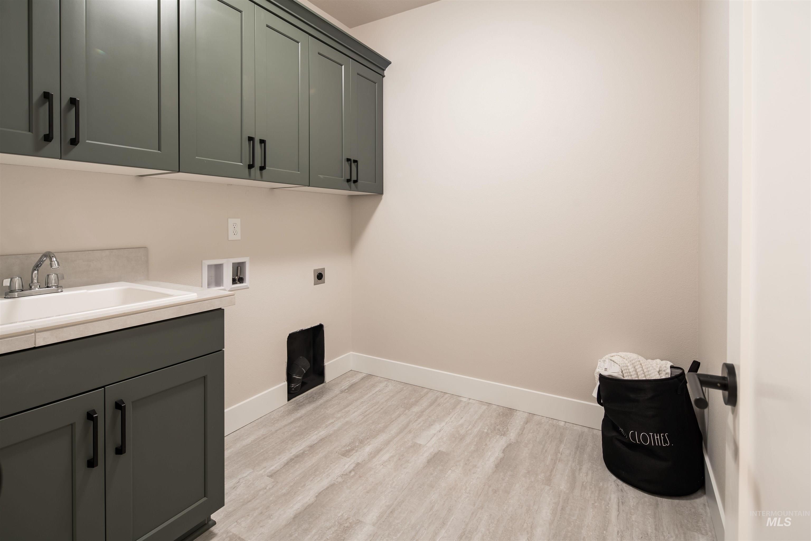 Laundry room featuring light wood-style floors, washer hookup, cabinet space, and electric dryer hookup