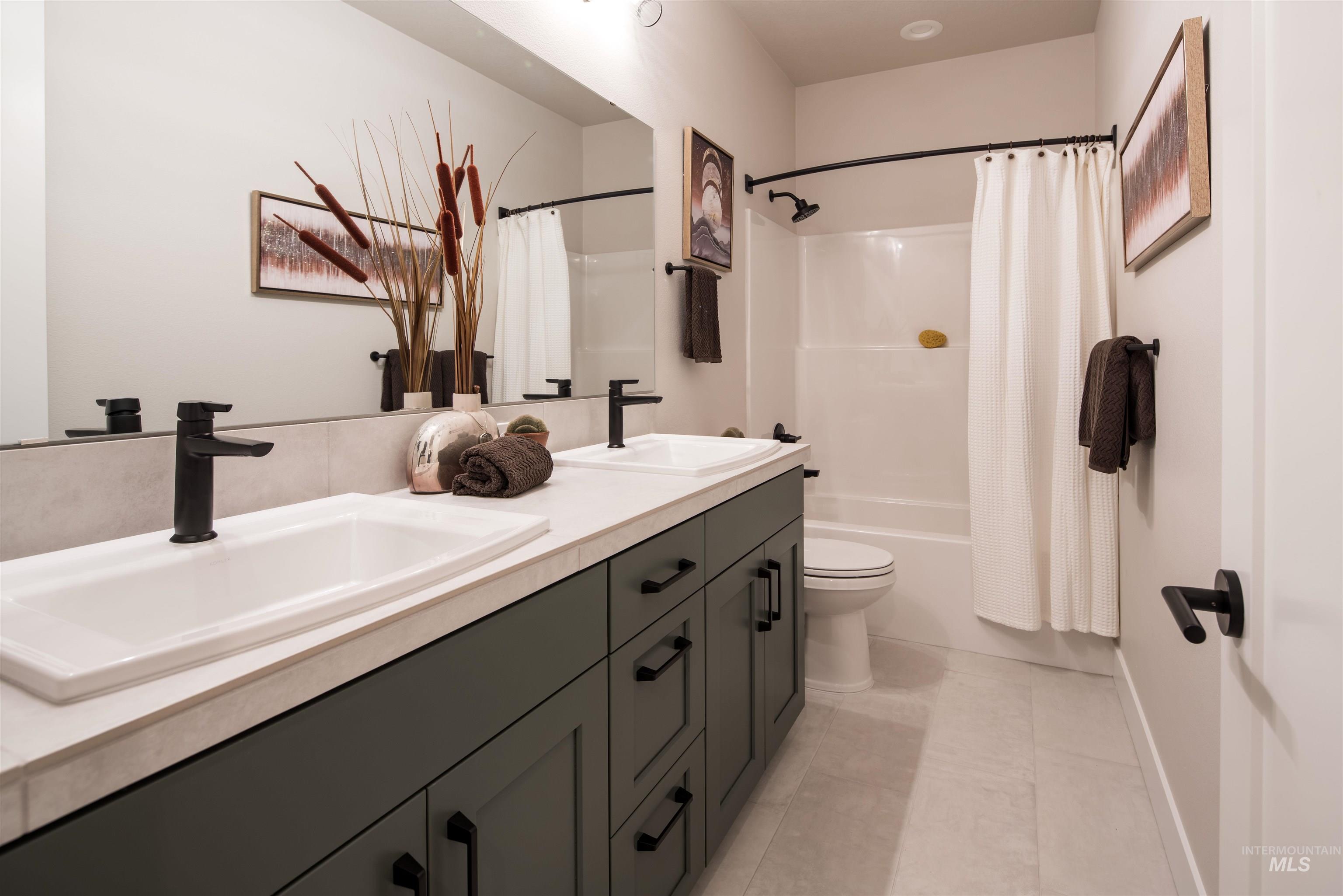 Full bathroom with shower / tub combo, double vanity, and light tile patterned floors