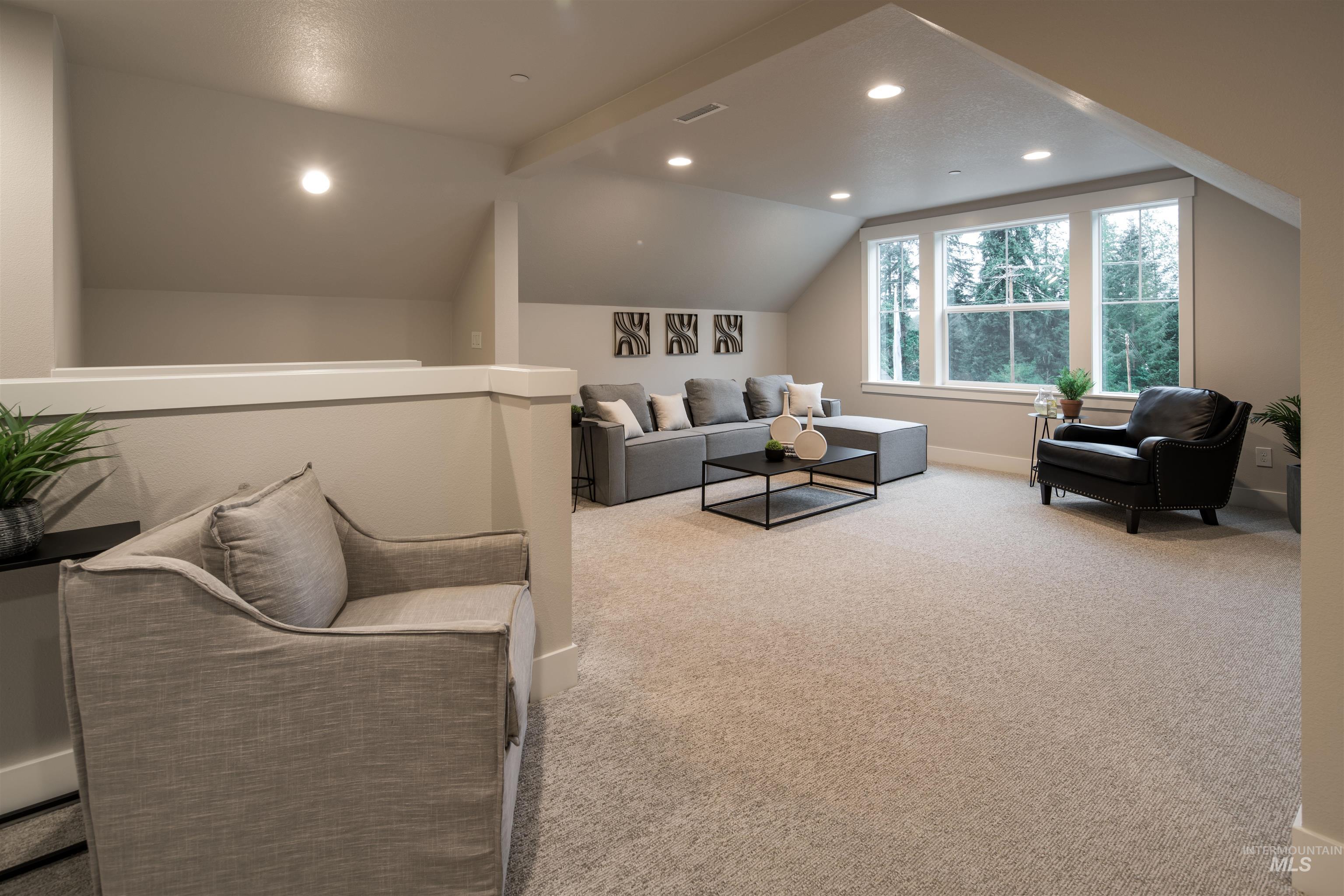Carpeted living area with vaulted ceiling and recessed lighting