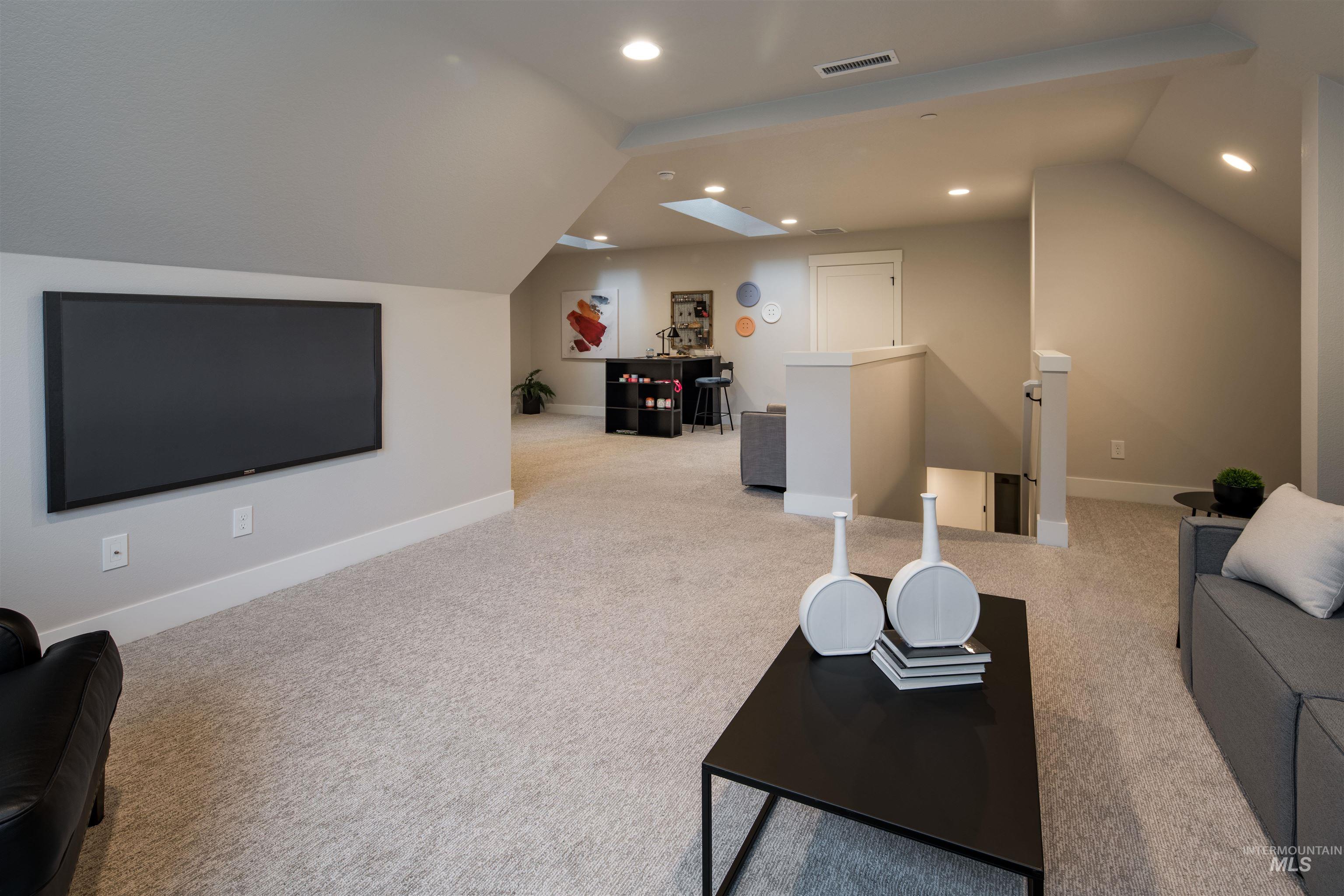 Home theater with vaulted ceiling, a skylight, light carpet, and recessed lighting