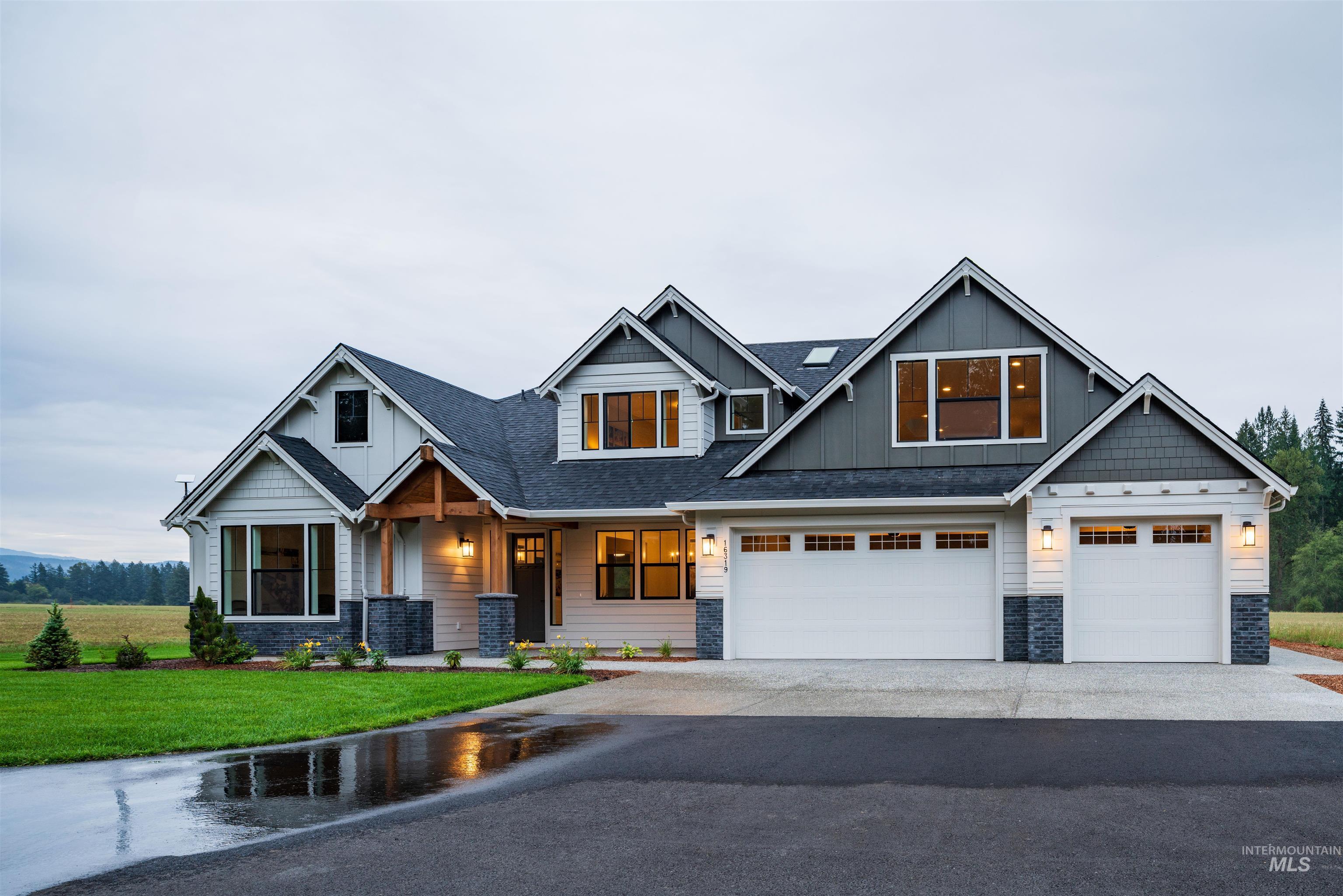 Craftsman house featuring board and batten siding, a front lawn, asphalt driveway, stone siding, and a shingled roof