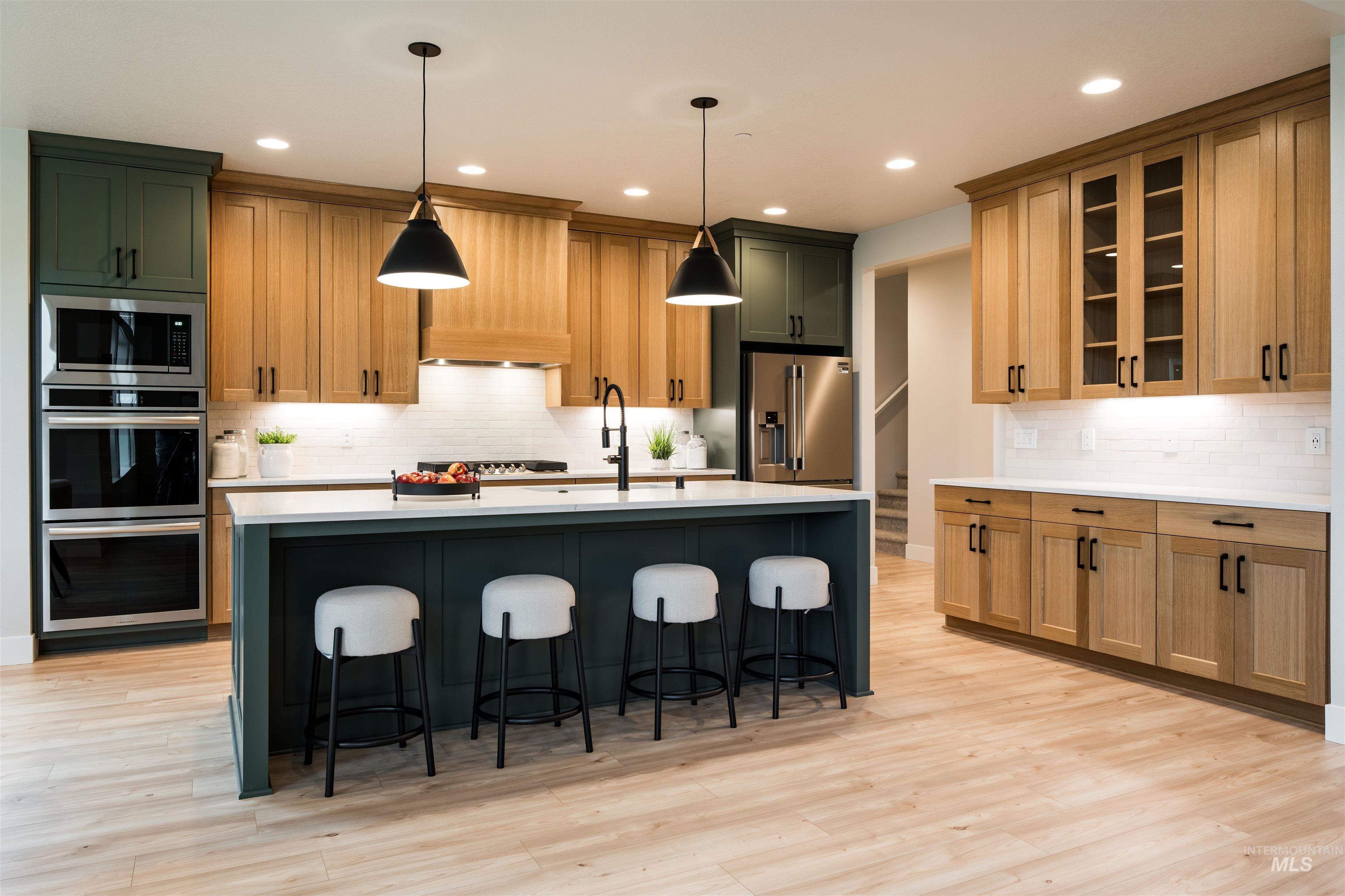 Kitchen featuring decorative backsplash, pendant lighting, appliances with stainless steel finishes, a breakfast bar, and recessed lighting