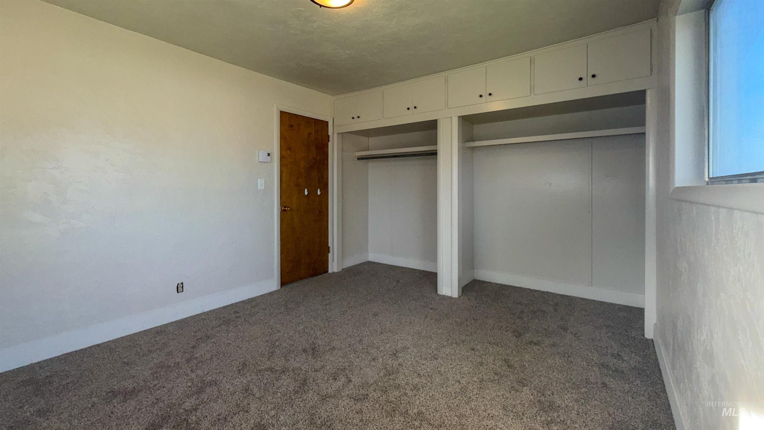 Unfurnished bedroom with dark carpet and multiple closets