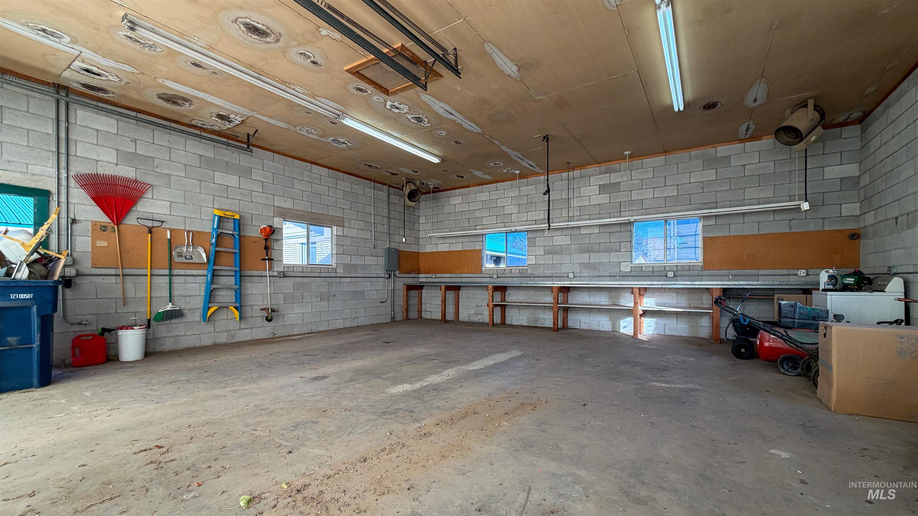 shop with concrete block wall, concrete flooring, and a garage