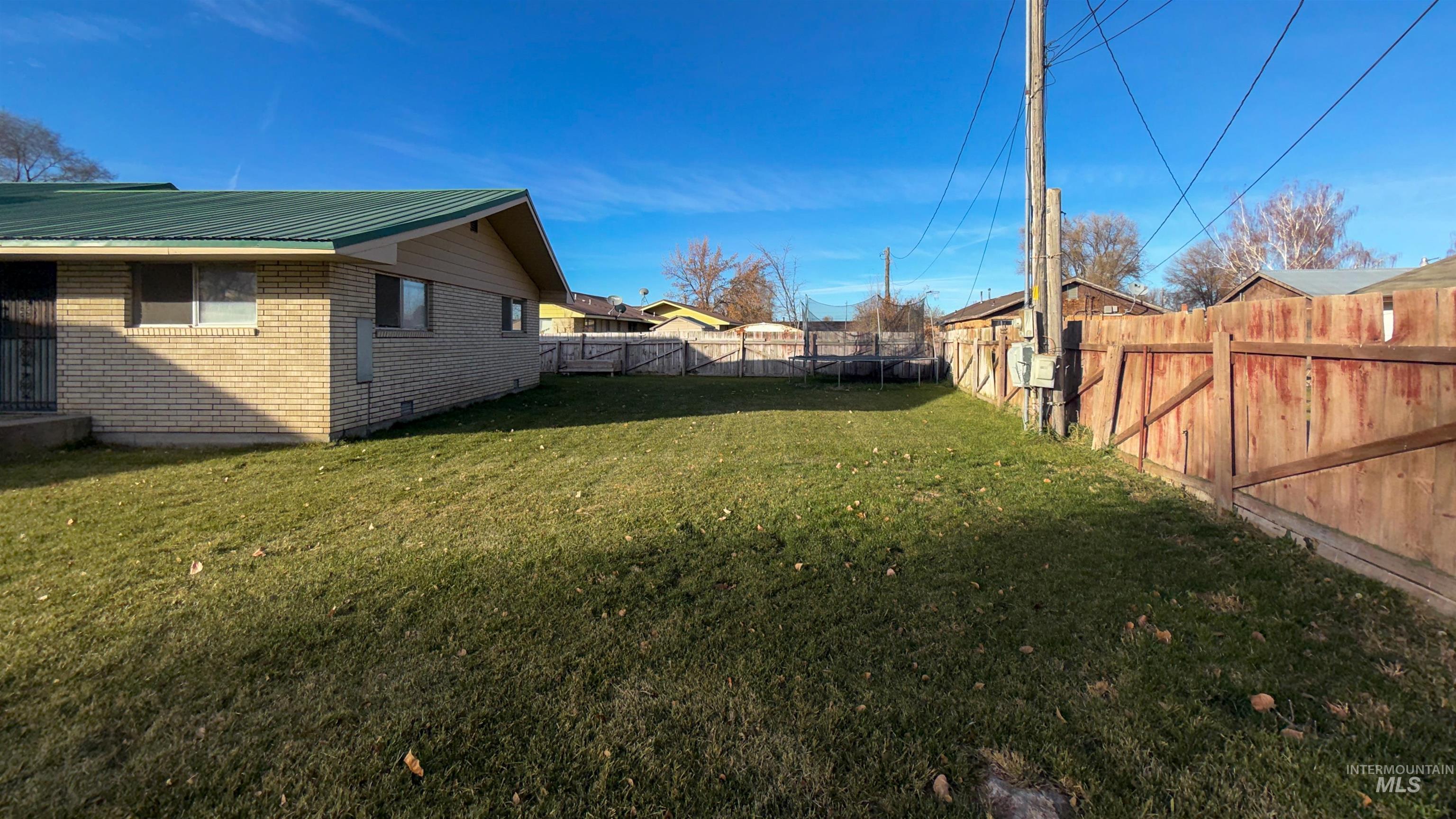 Fenced backyard featuring a trampoline