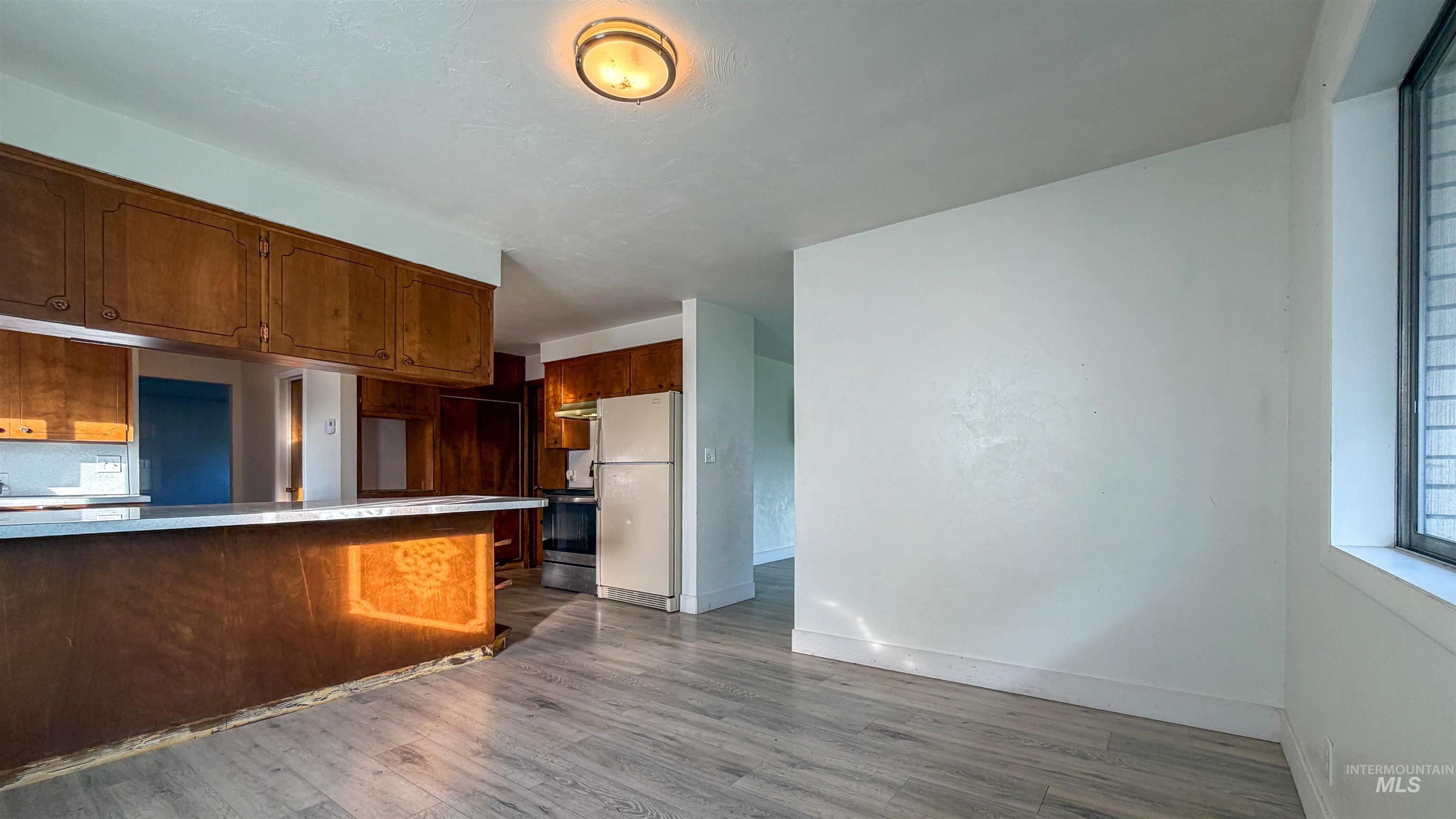 Kitchen with freestanding refrigerator, brown cabinets, and light countertops