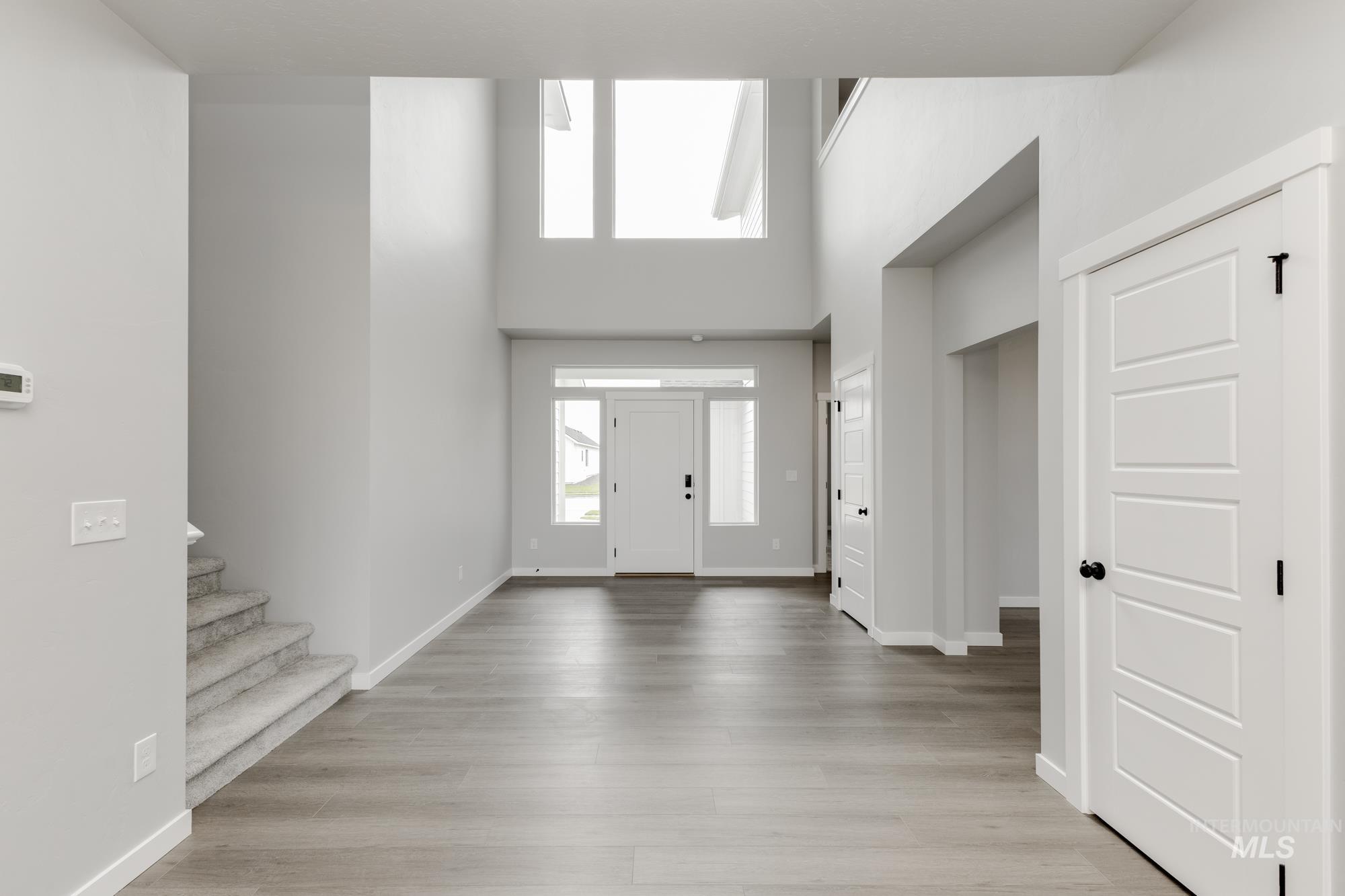 Foyer entrance with a high ceiling, stairs, and light wood-style floors