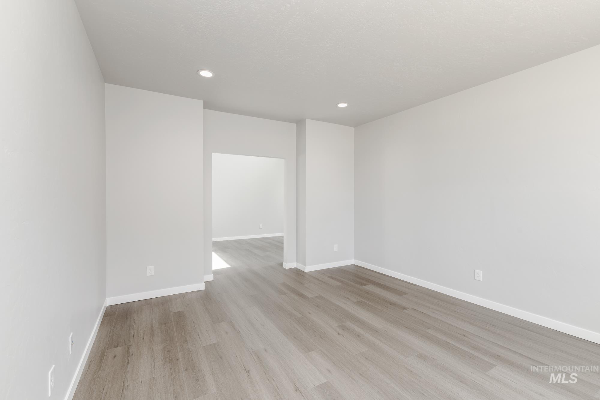Empty room featuring light wood-type flooring and recessed lighting