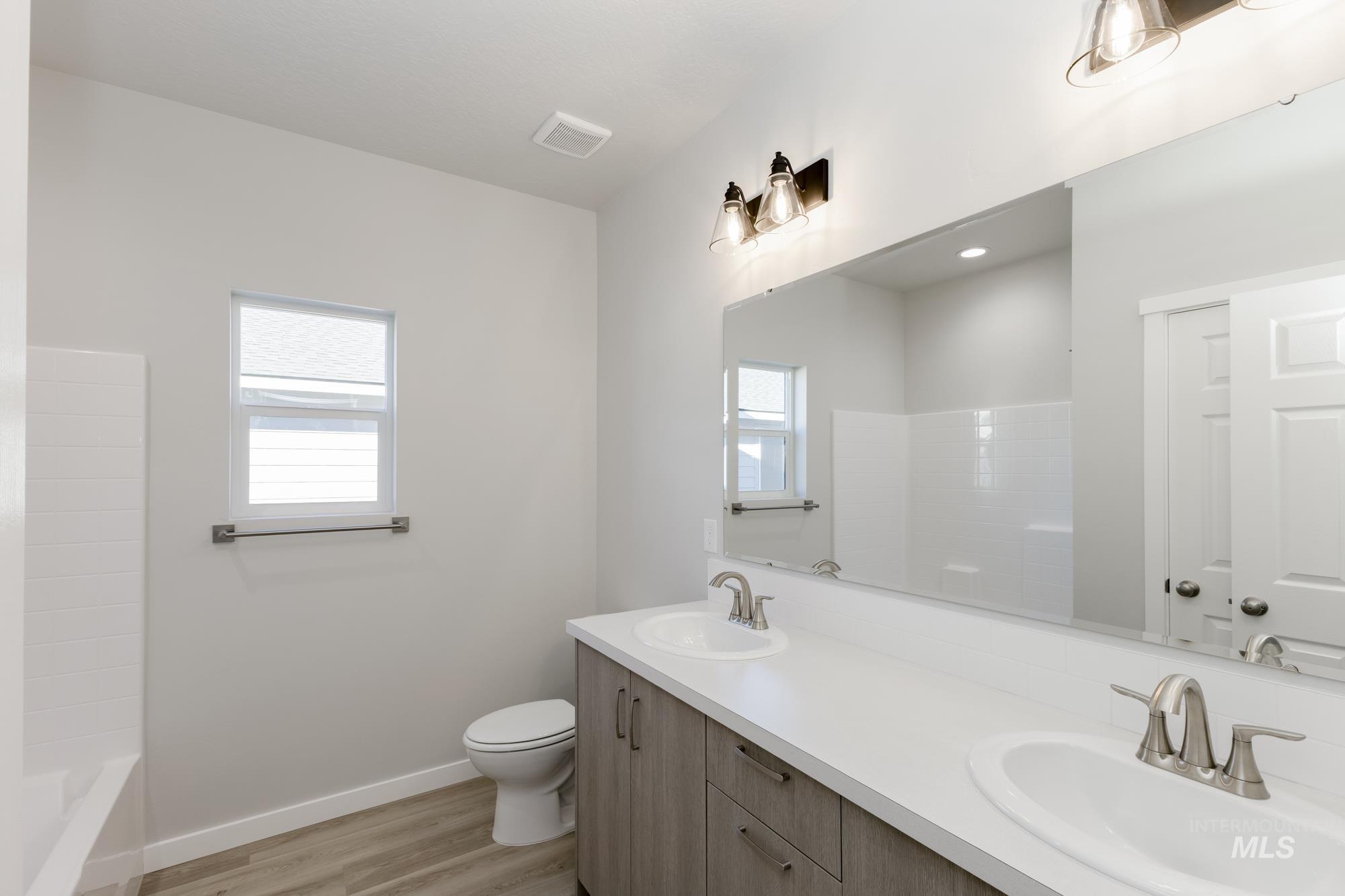 Bathroom featuring double vanity, light wood-style flooring, and shower / tub combination