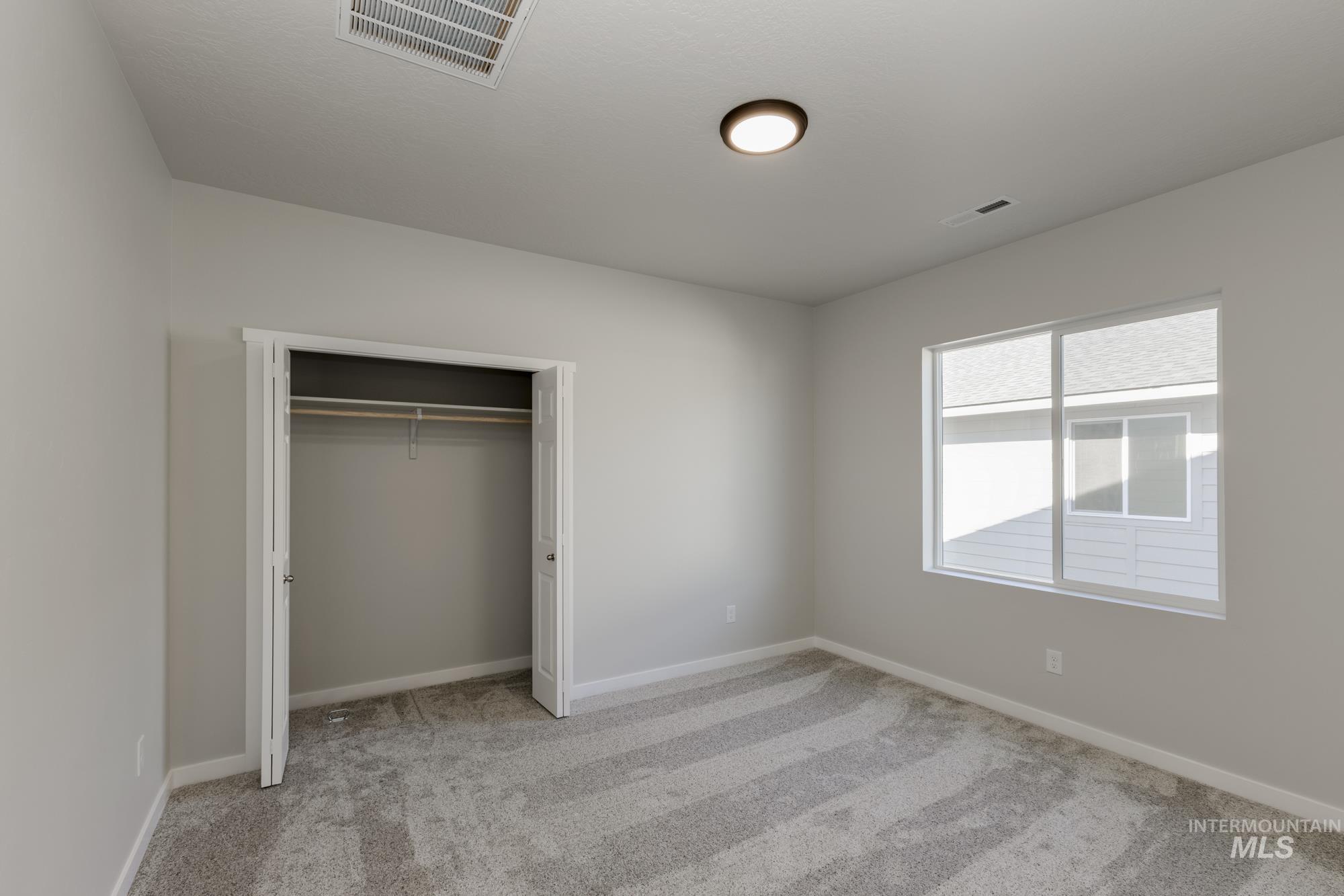 Unfurnished bedroom with light carpet and a closet
