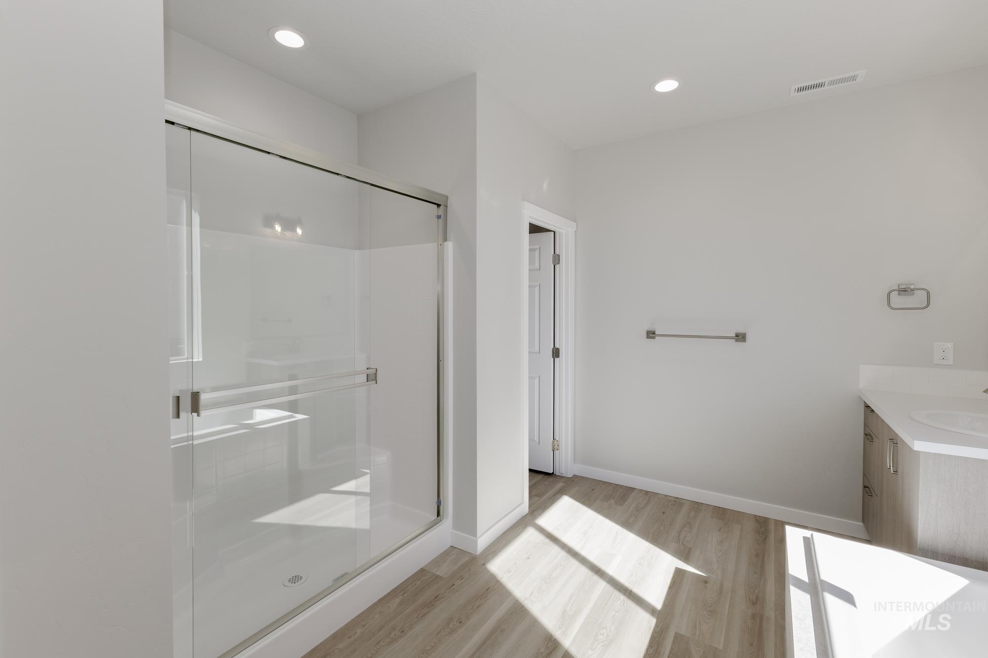 Full bath featuring vanity, light wood-style flooring, a stall shower, and recessed lighting