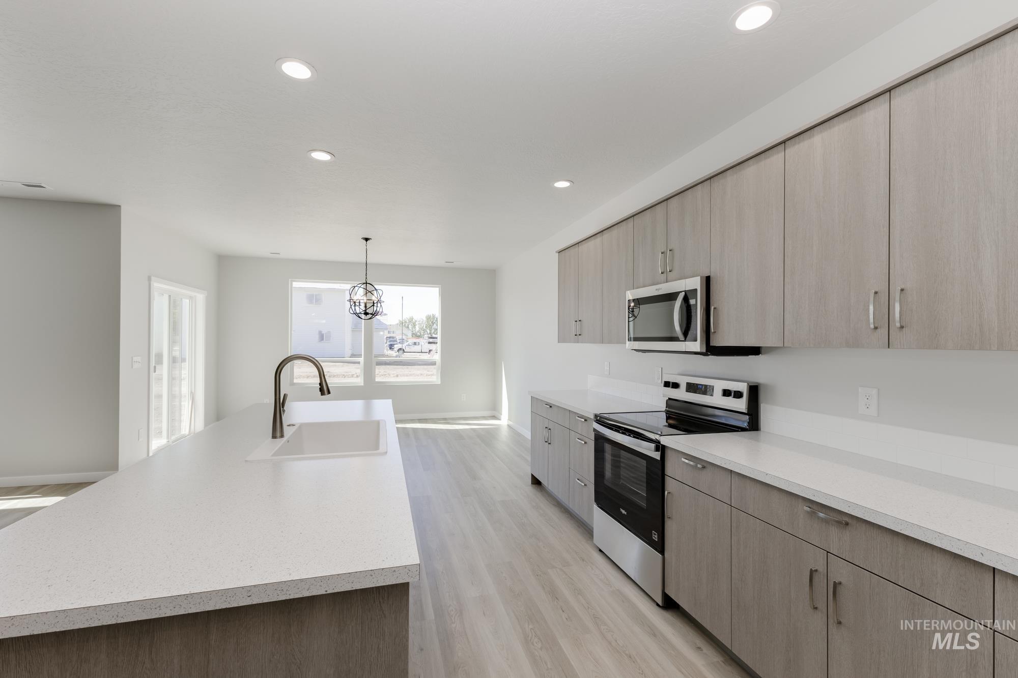 Kitchen featuring stainless steel appliances, light wood-style floors, light brown cabinetry, light countertops, and recessed lighting