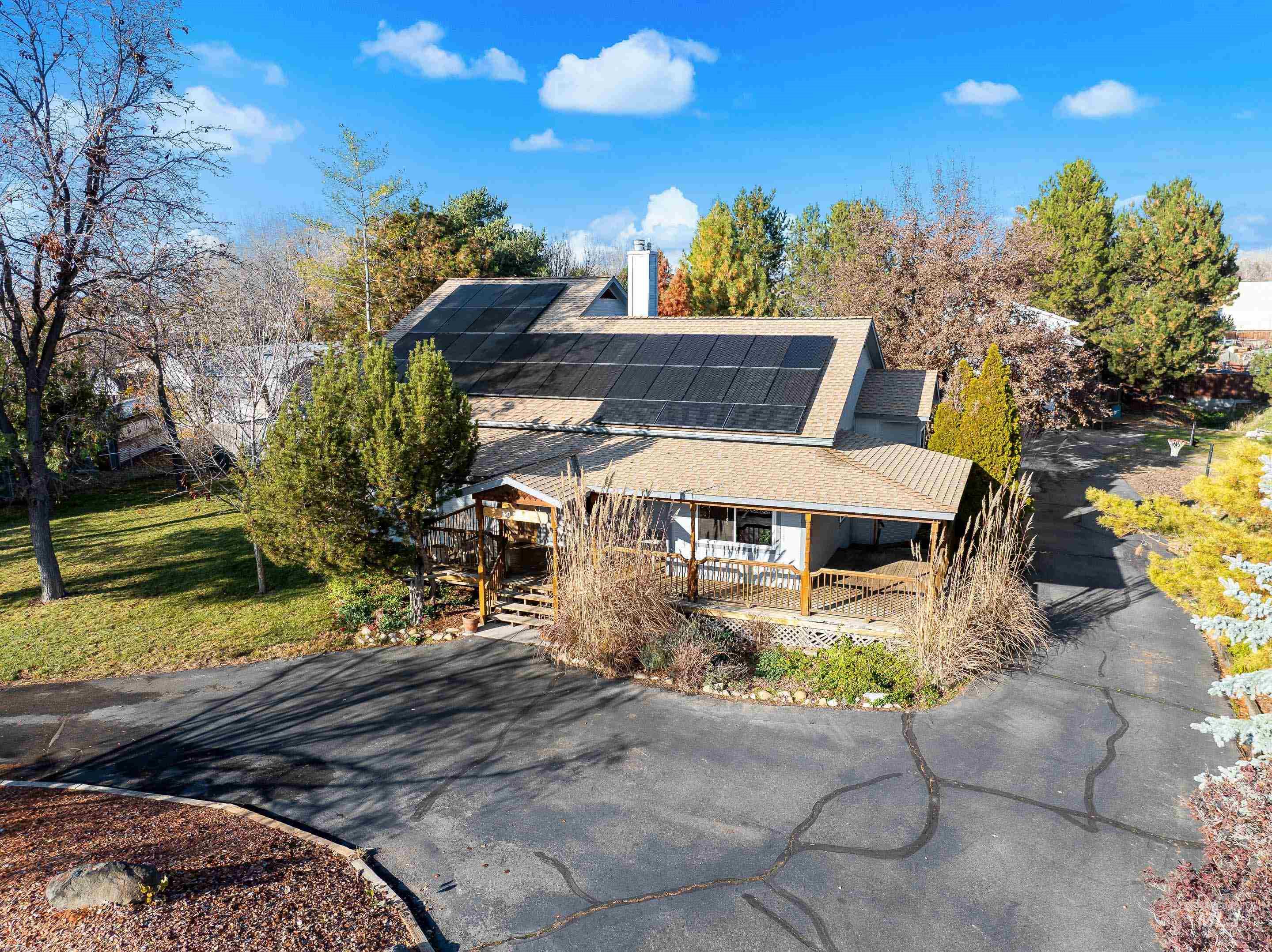View of front of house featuring solar panels, roof with shingles, a front yard, and a chimney