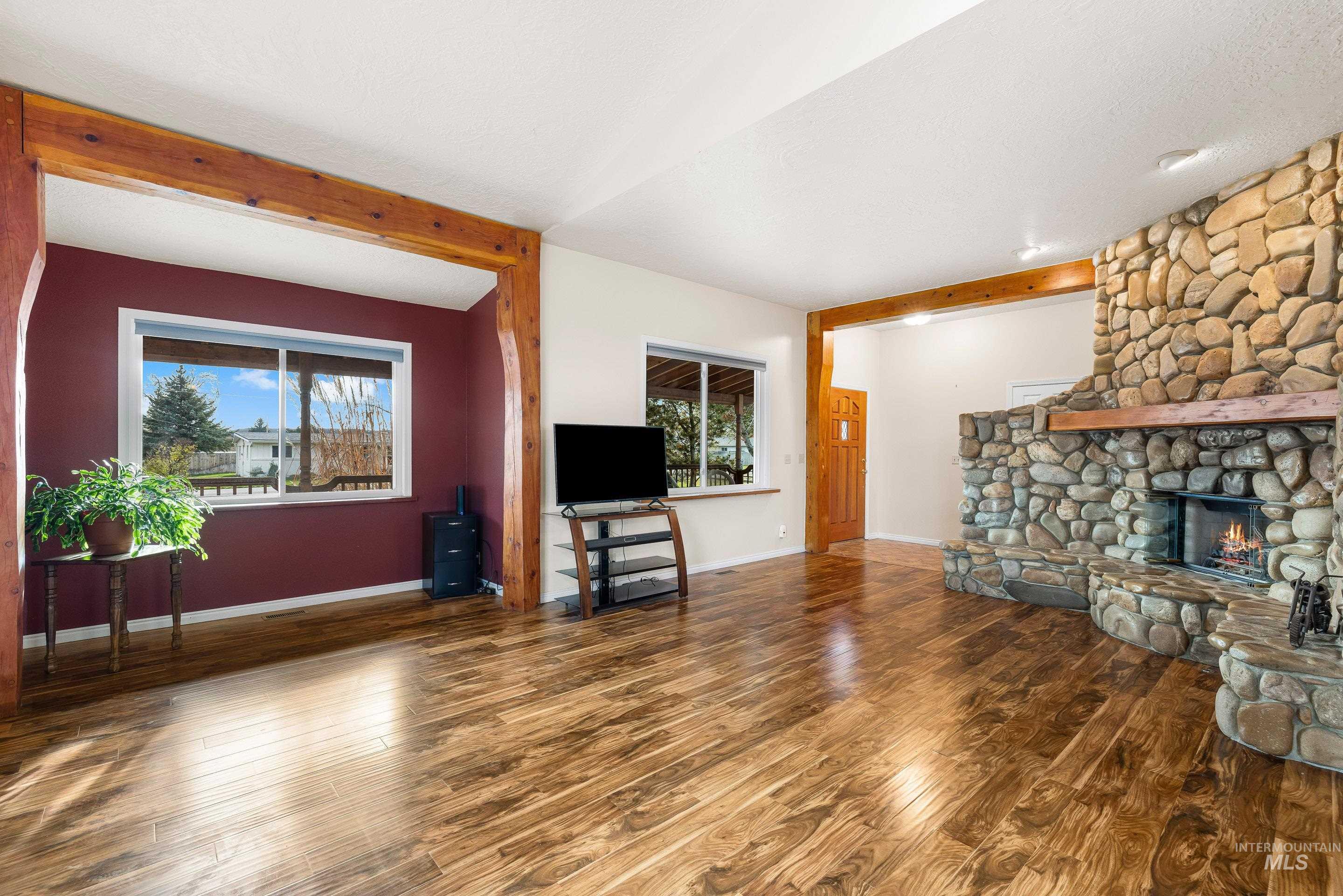 Living area featuring wood finished floors, plenty of natural light, a fireplace, and beam ceiling