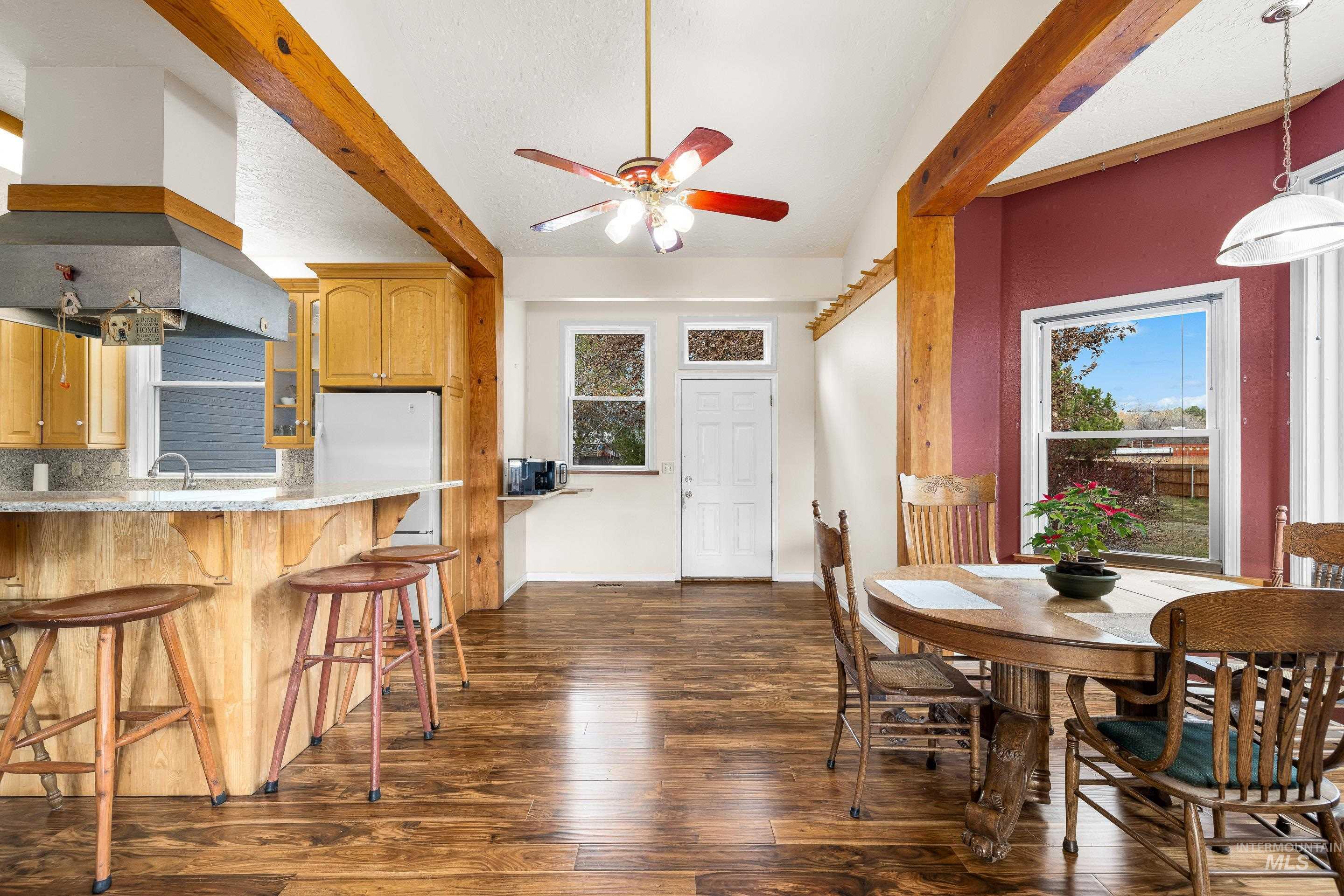 Dining room featuring beam ceiling, ceiling fan, dark wood-type flooring, and healthy amount of natural light