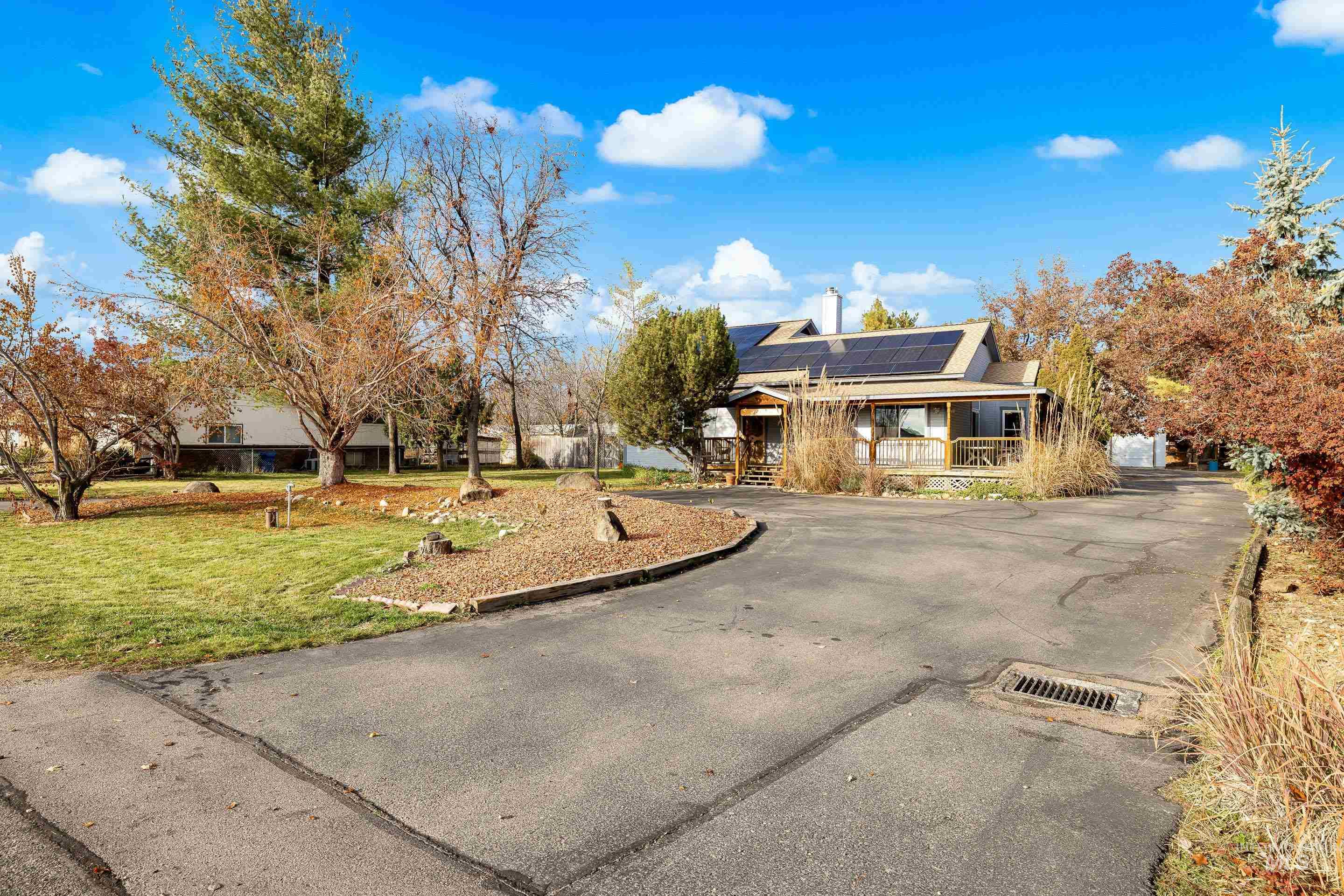 View of front of home with roof mounted solar panels, a front yard, and a chimney