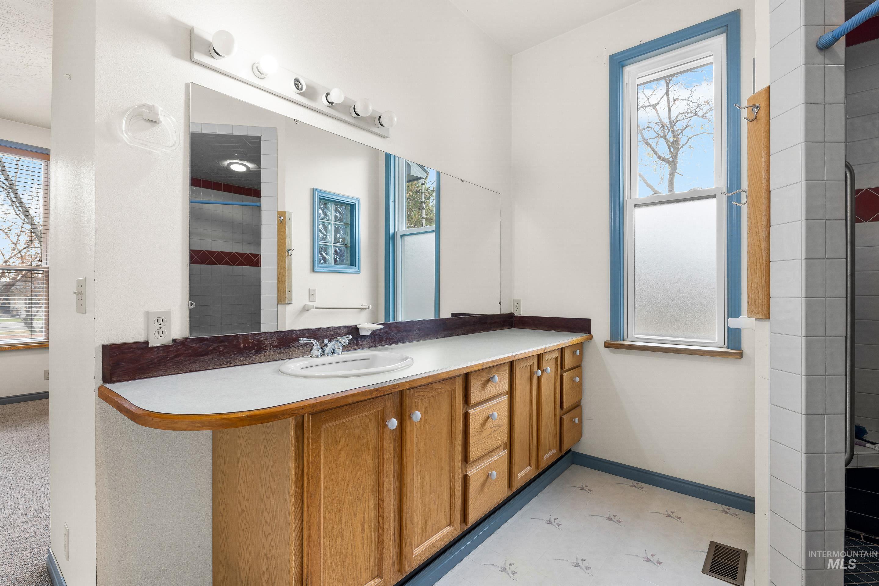 Bathroom featuring tiled shower, vanity, healthy amount of natural light, and light flooring
