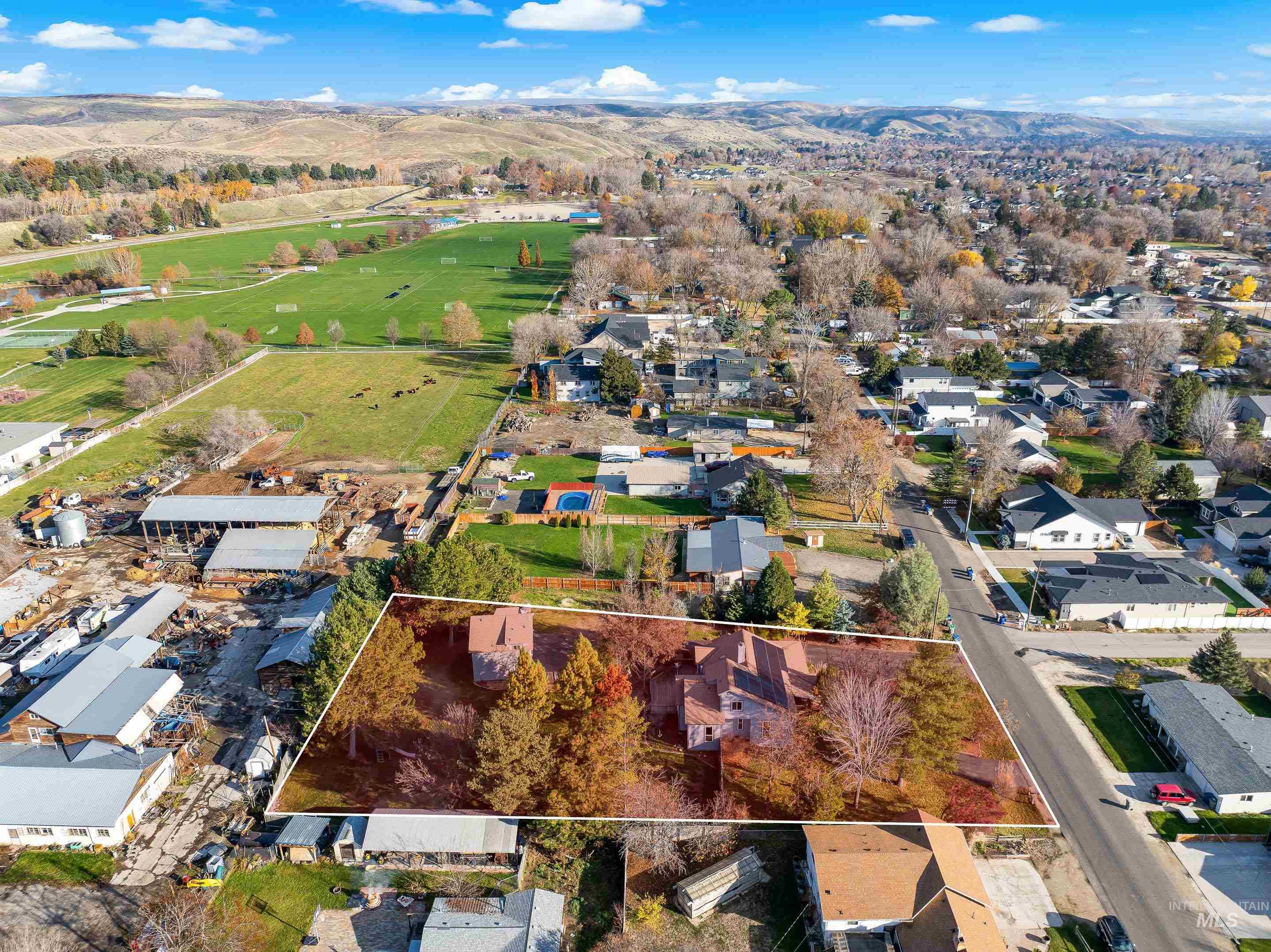 Aerial view of residential area with property parcel outlined and a mountain backdrop