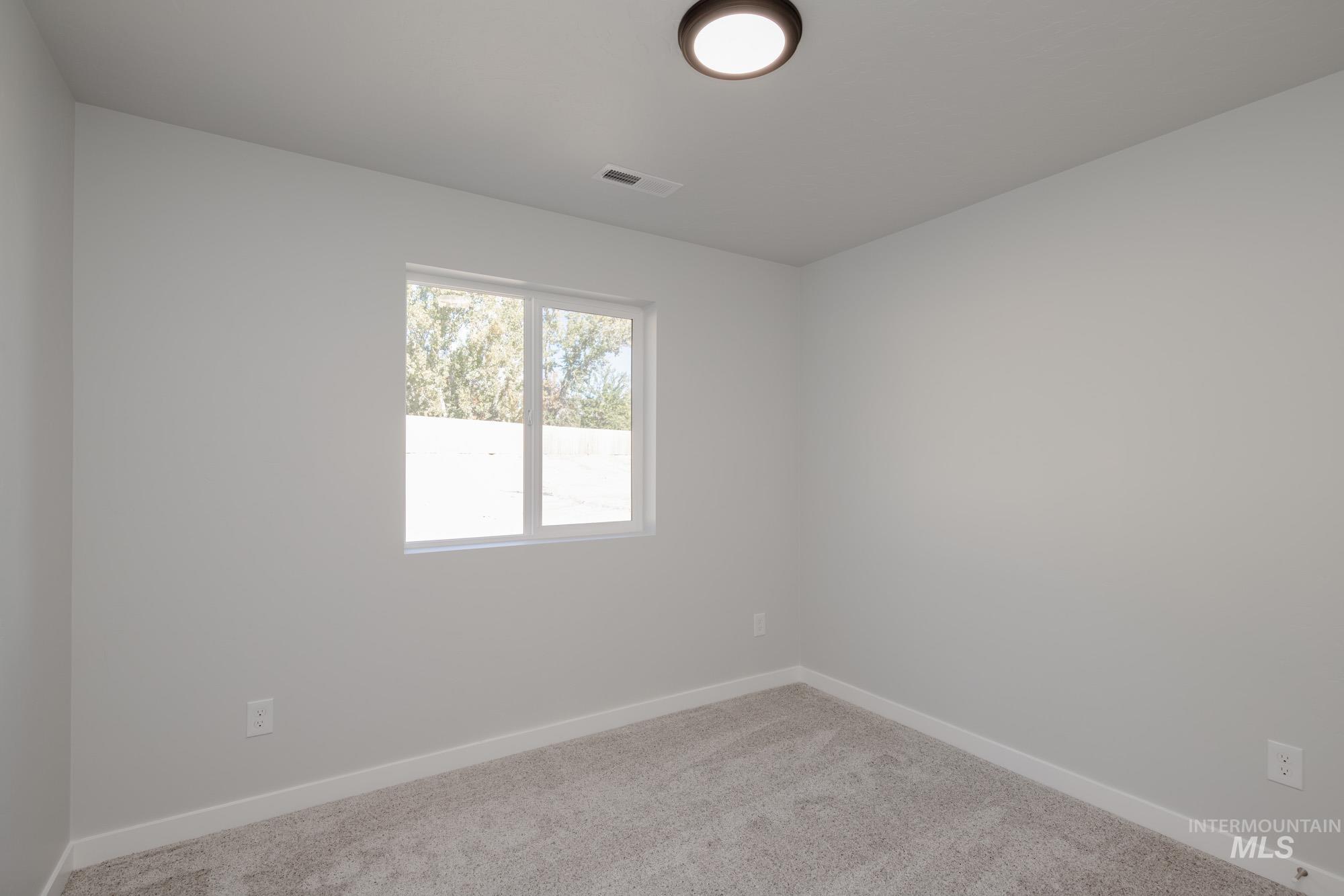 Spare room featuring carpet flooring and baseboards