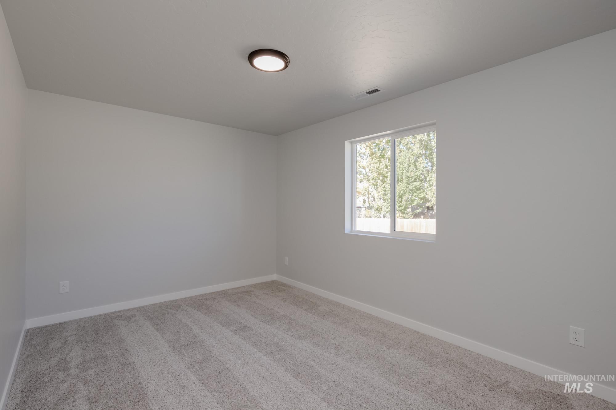 Spare room with light carpet and baseboards