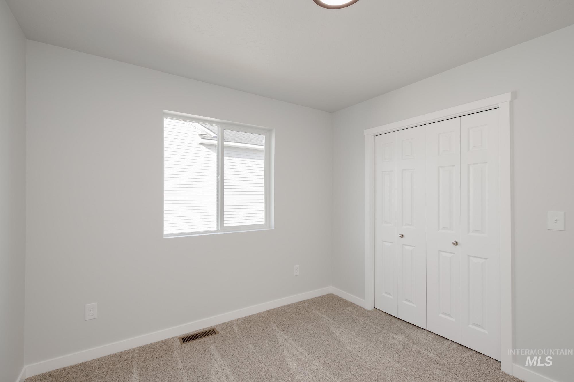 Unfurnished bedroom featuring light carpet and a closet