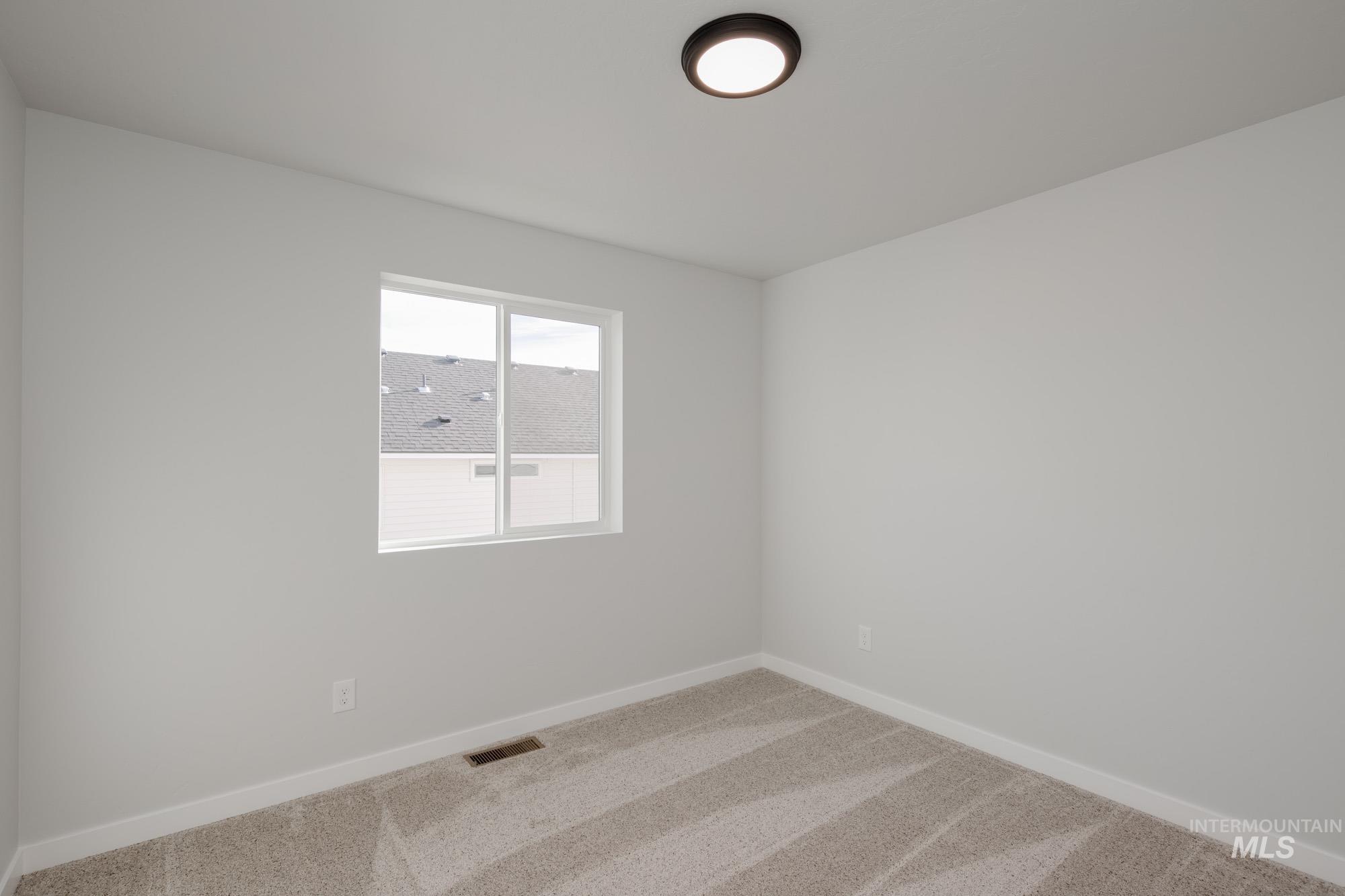 Carpeted spare room featuring baseboards