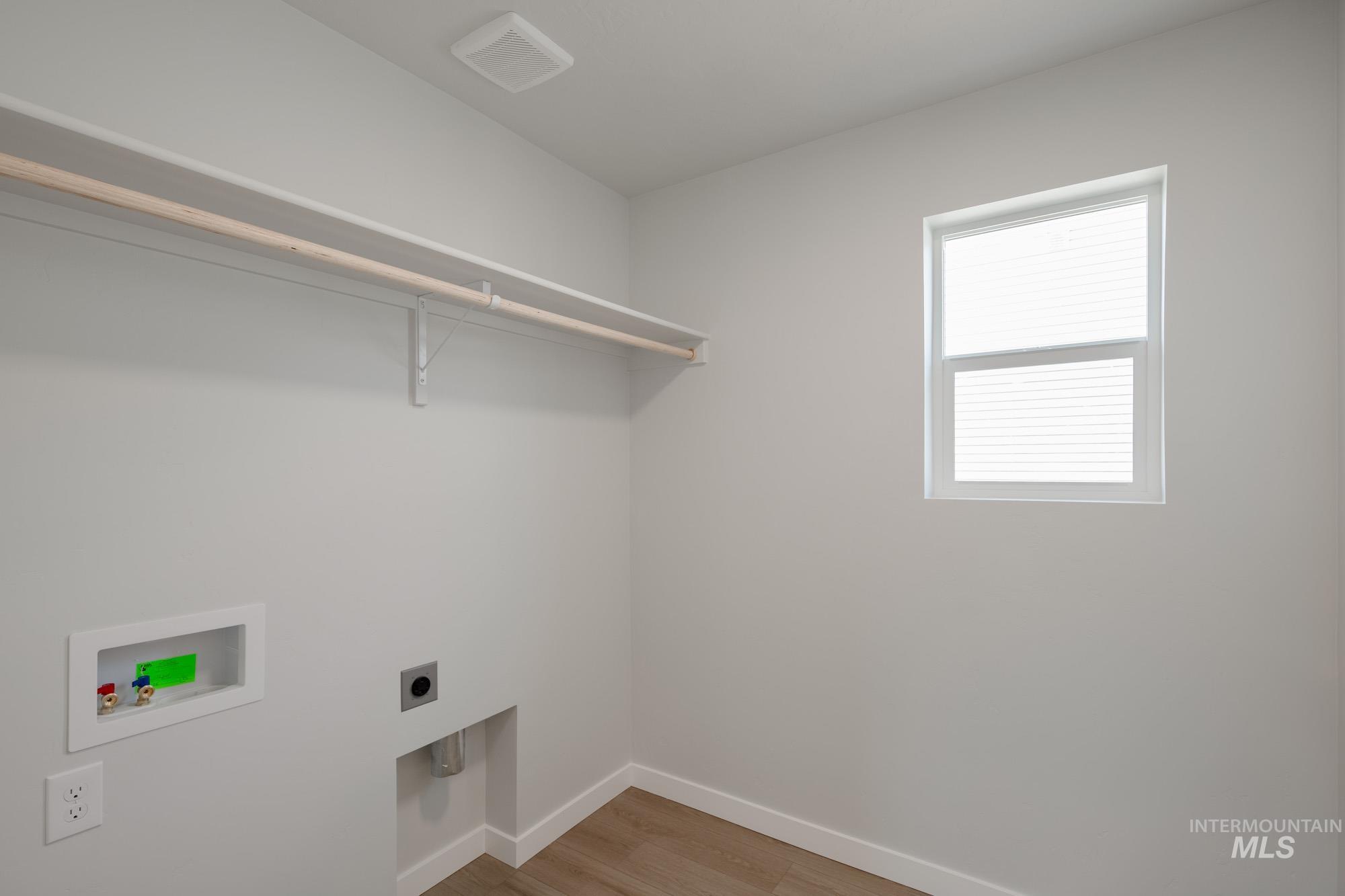 Laundry room with light wood-style flooring, hookup for a washing machine, and electric dryer hookup