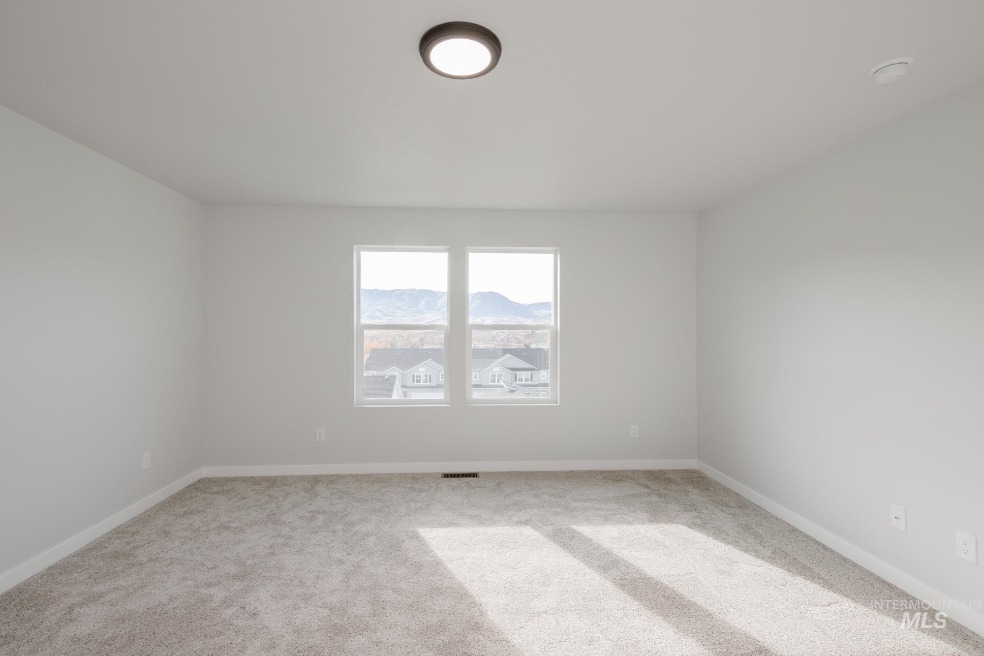 Carpeted spare room with baseboards and a mountain view