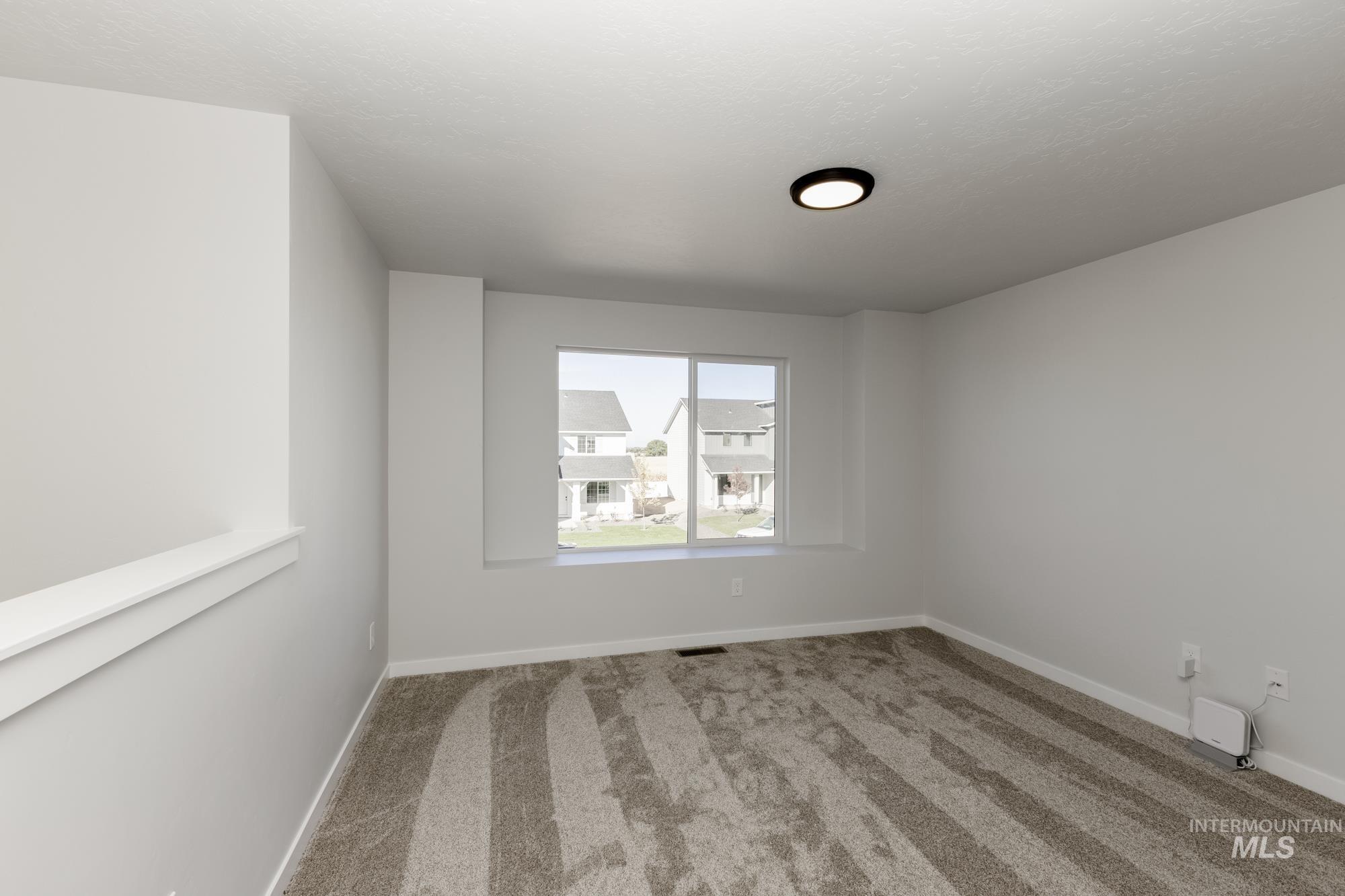 Empty room featuring carpet and baseboards