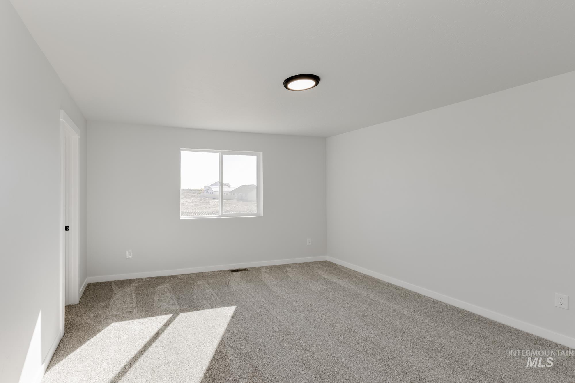 Carpeted spare room featuring baseboards