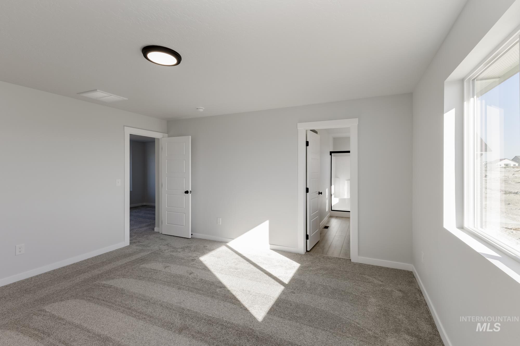 Unfurnished bedroom with light colored carpet and ensuite bath