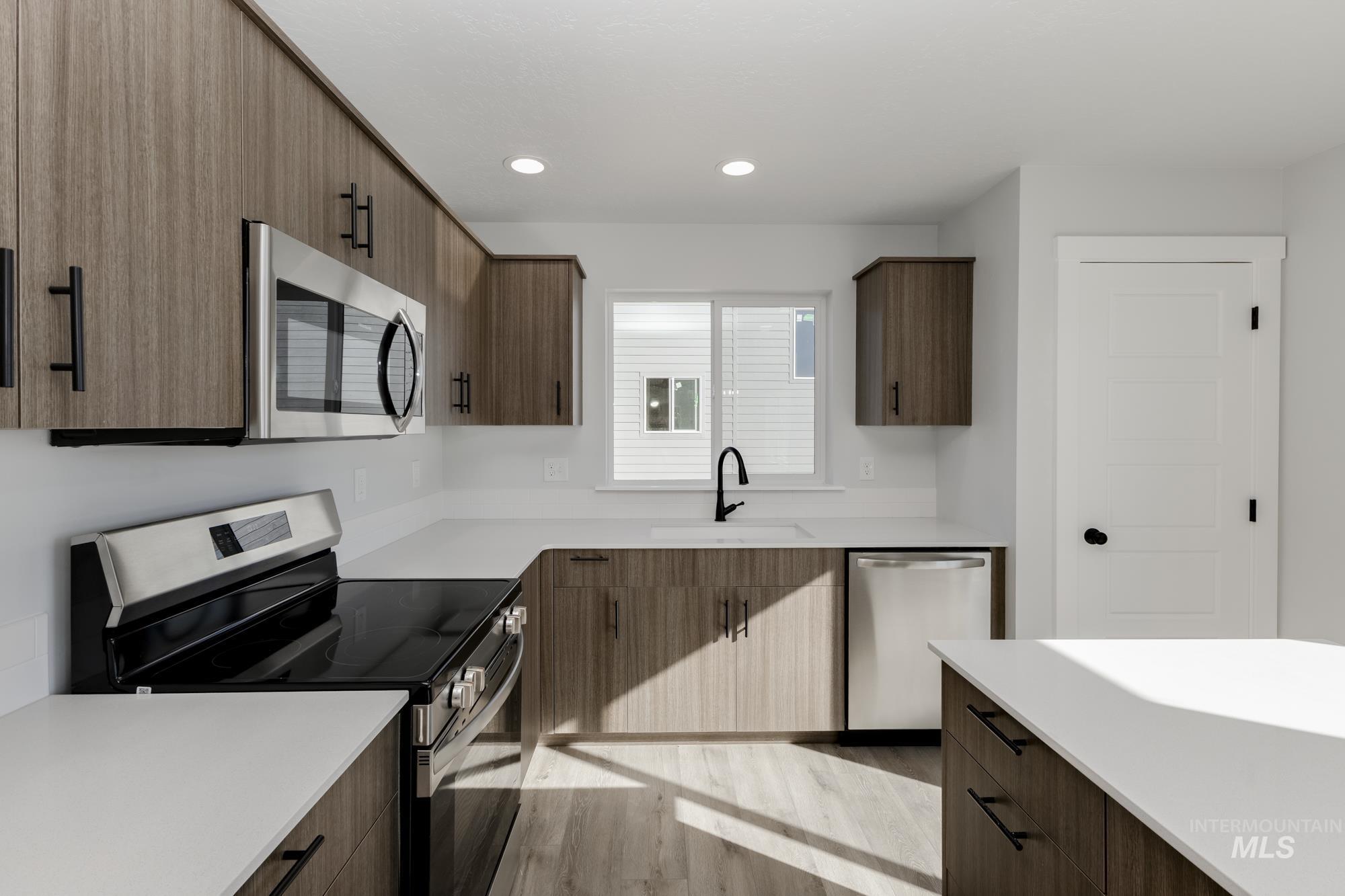 Kitchen with appliances with stainless steel finishes, light wood finished floors, modern cabinets, recessed lighting, and light stone countertops