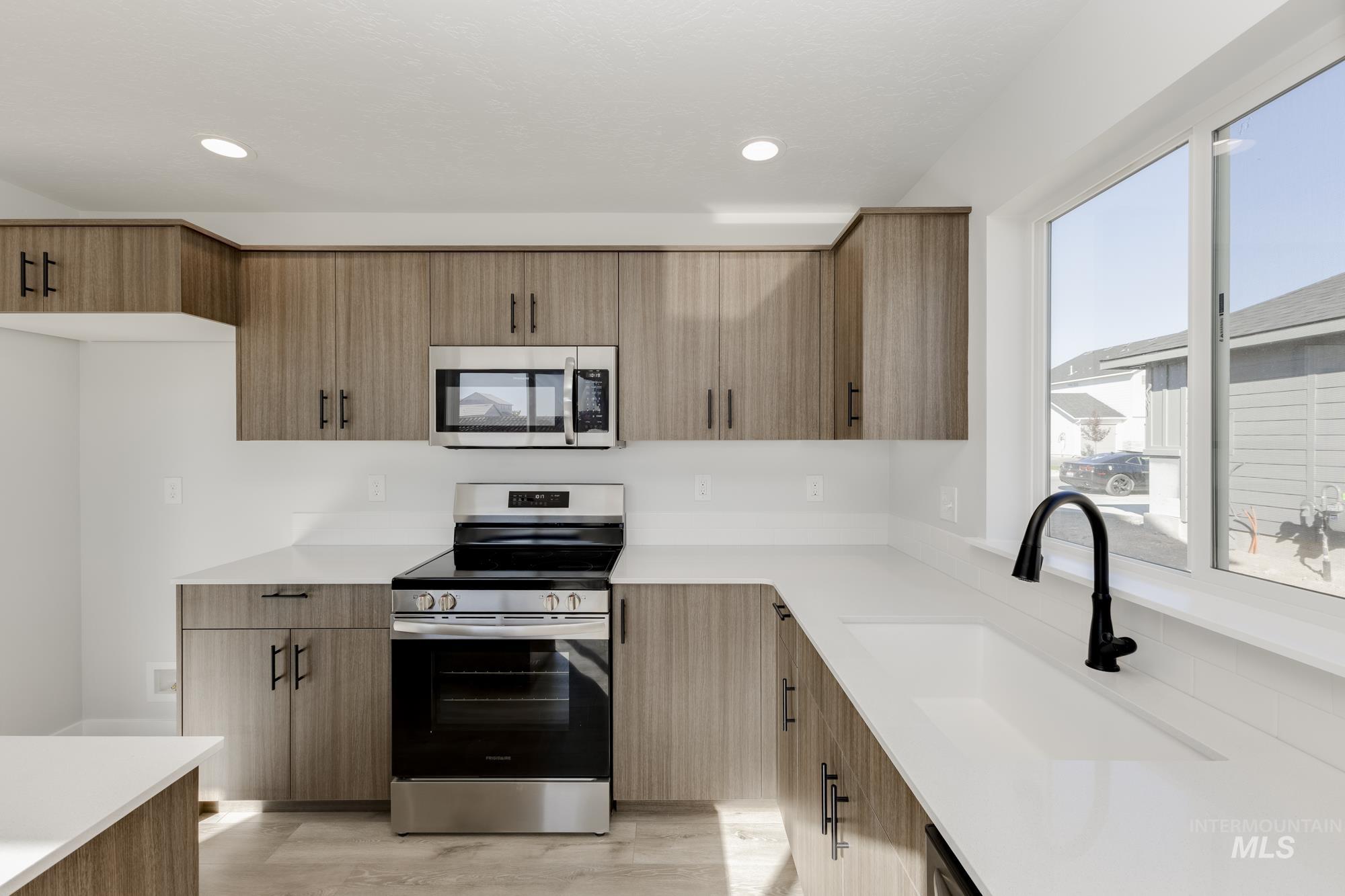 Kitchen with stainless steel appliances, light wood-type flooring, light stone counters, modern cabinets, and recessed lighting