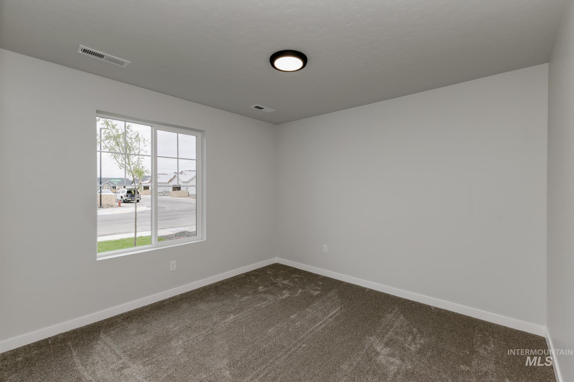 Unfurnished room featuring dark colored carpet and baseboards