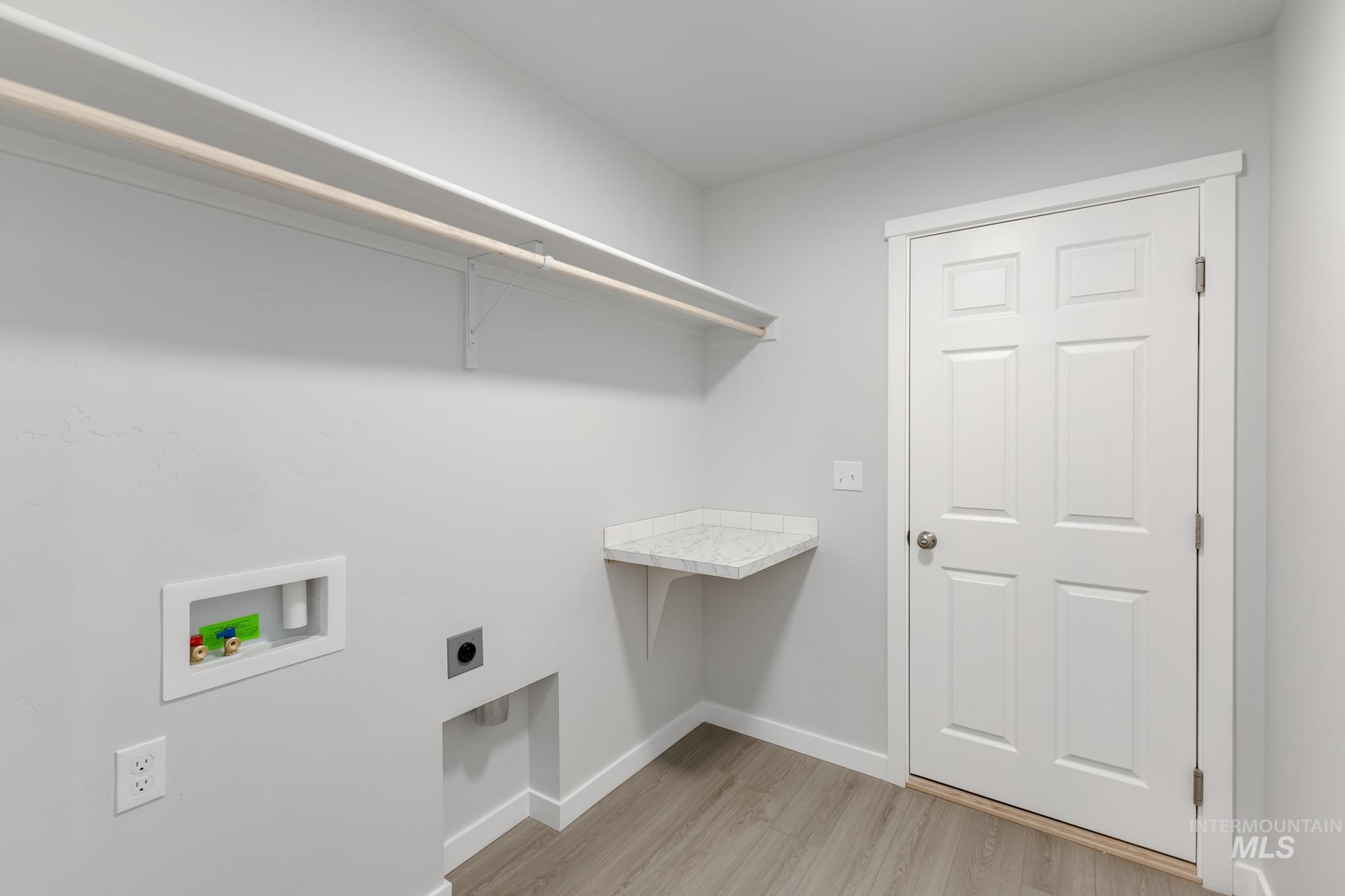 Washroom with light wood-type flooring, hookup for a washing machine, and electric dryer hookup