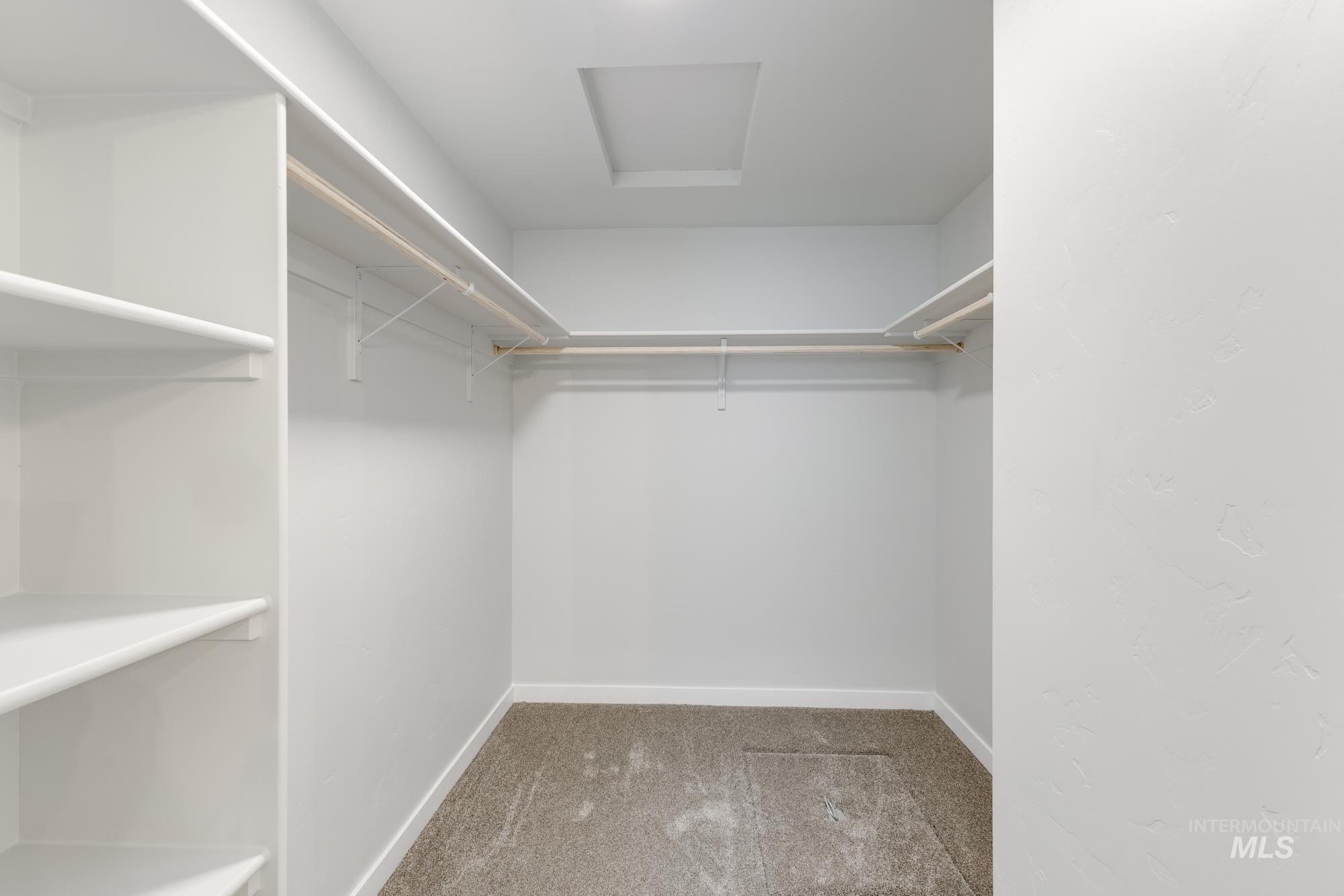 Spacious closet with light carpet and attic access