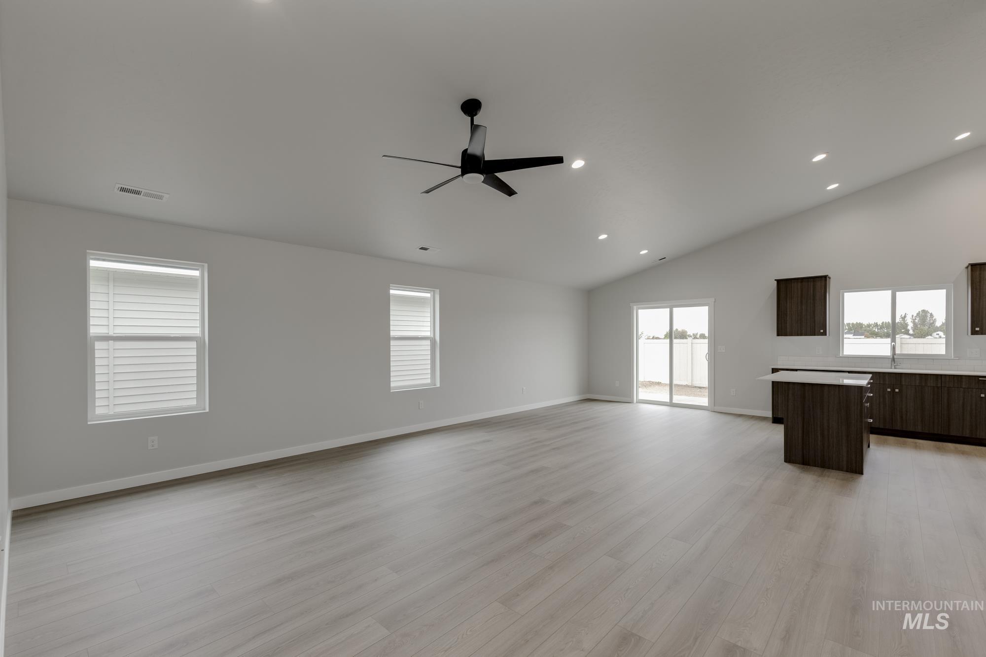 Unfurnished living room with light wood finished floors, ceiling fan, recessed lighting, and high vaulted ceiling