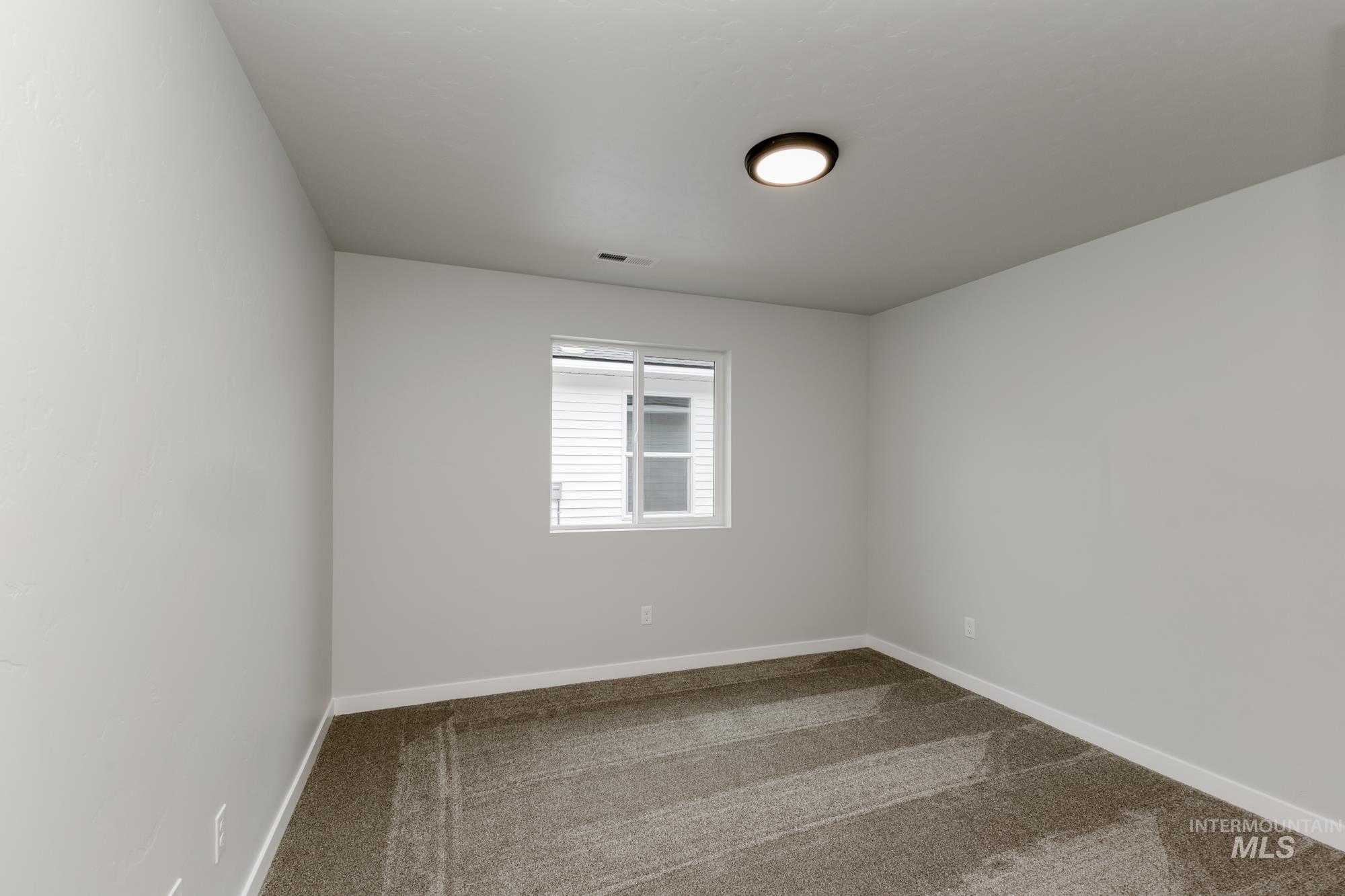 Unfurnished room featuring dark colored carpet and baseboards