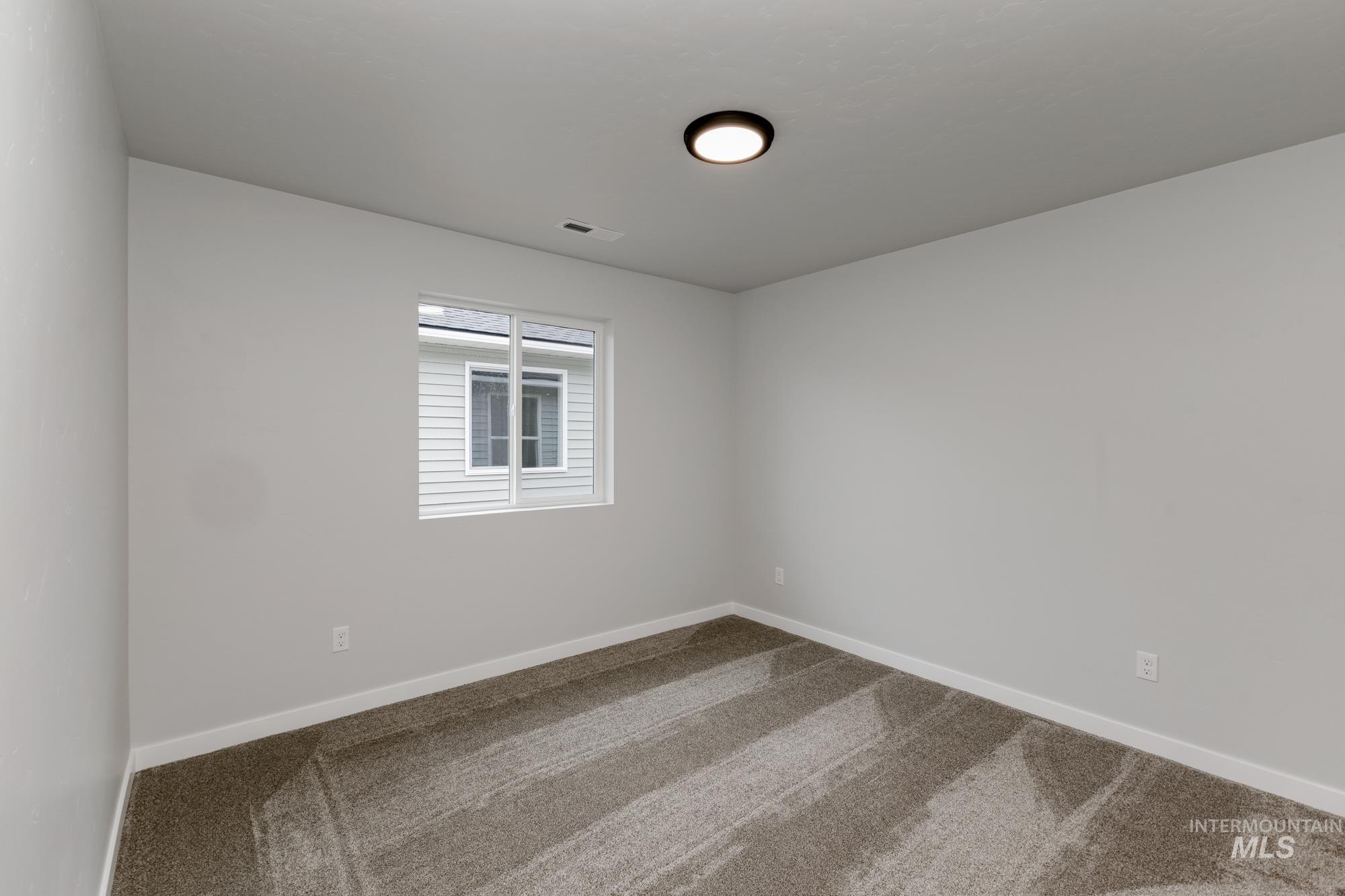 Carpeted spare room featuring baseboards