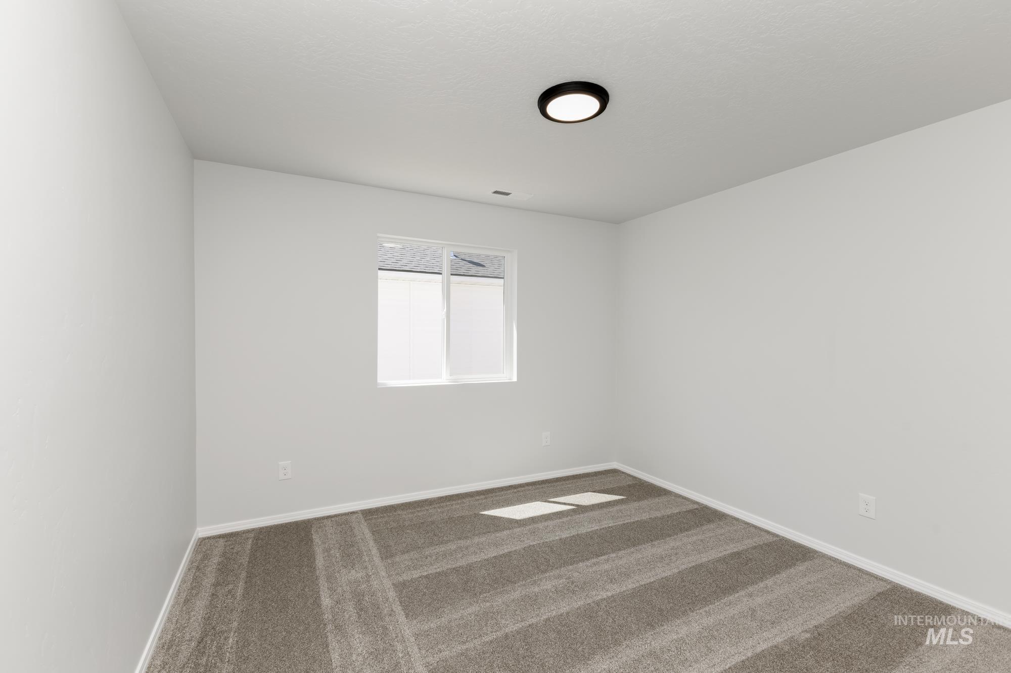 Carpeted spare room with baseboards
