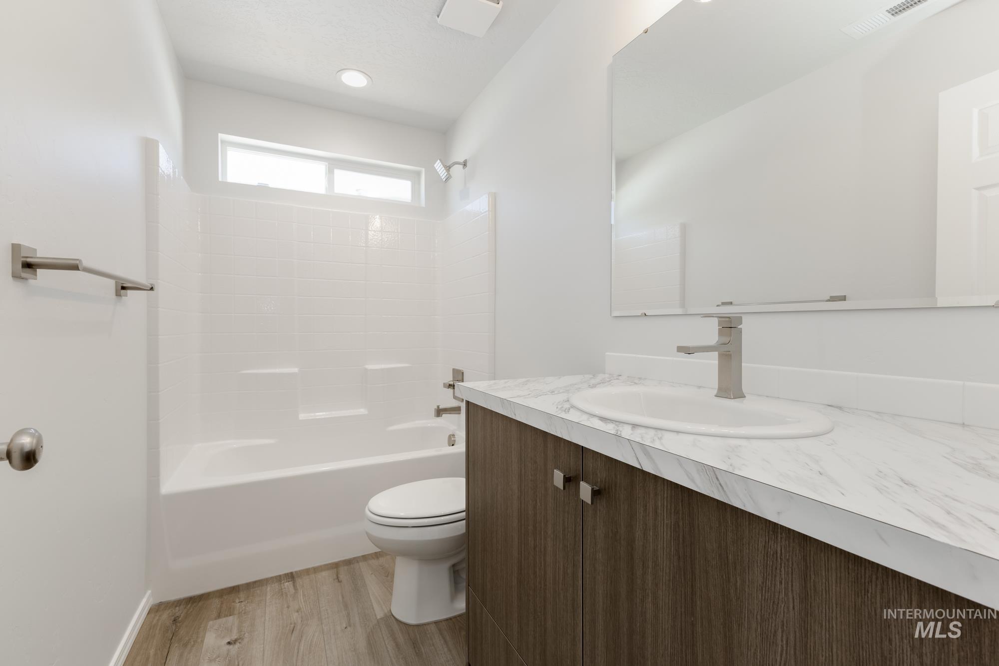 Full bath featuring bathtub / shower combination, vanity, and light wood-style floors