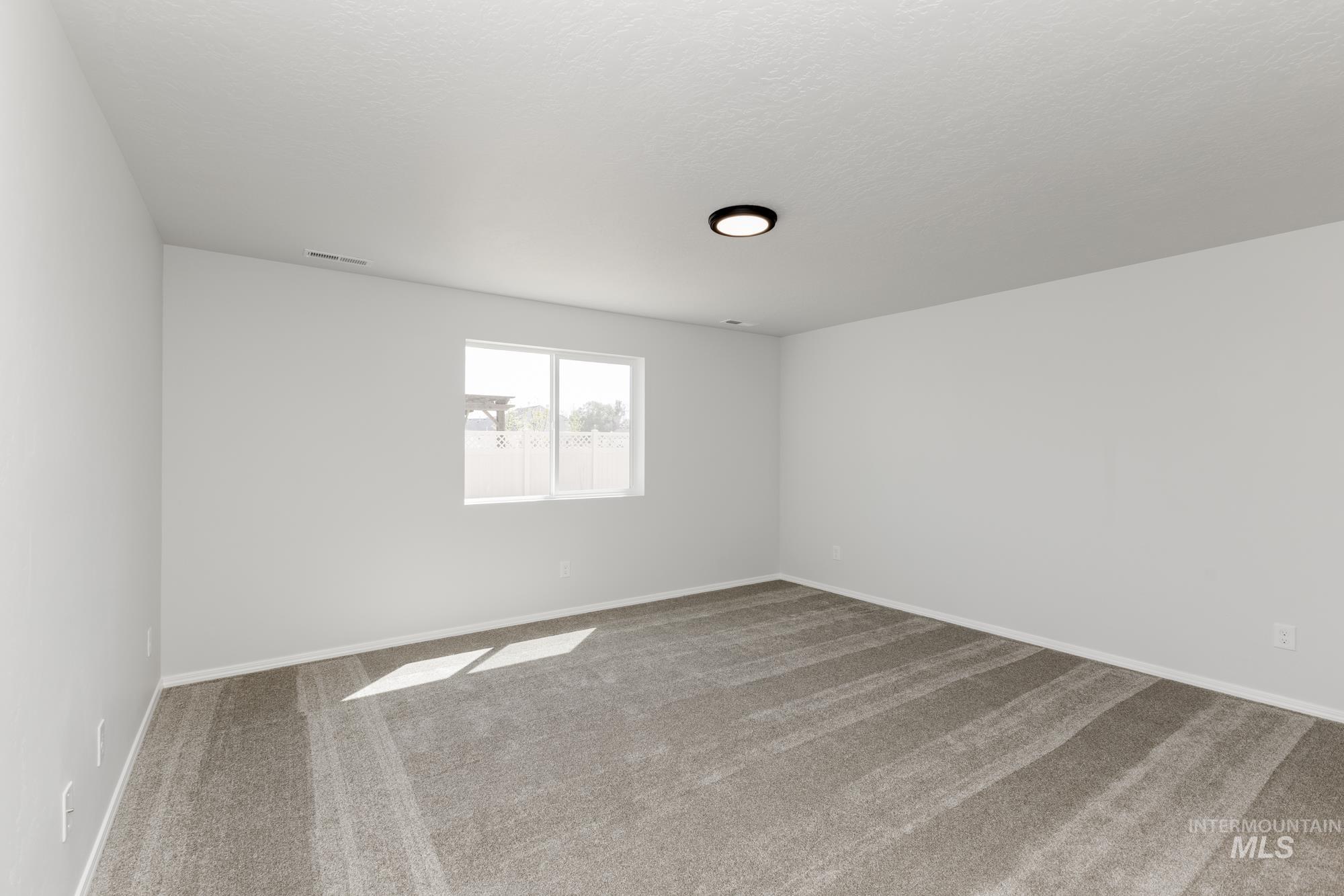 Empty room with carpet floors and a textured ceiling
